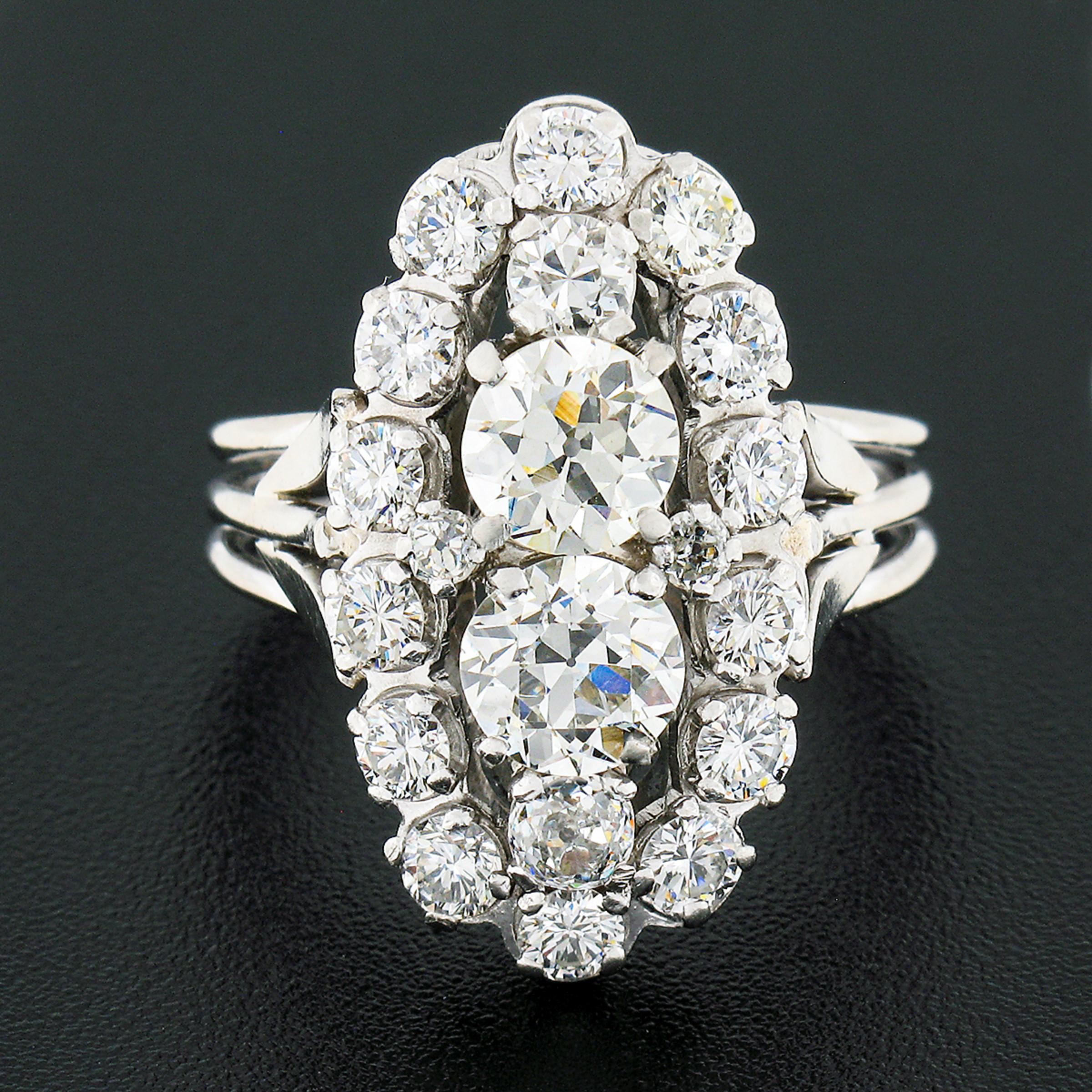 This magnificent vintage dinner ring was crafted from solid 18k white gold and features an elongated oval shaped top drenched with absolutely stunning diamonds throughout. Two old European cut diamonds stand out at the open center with their very