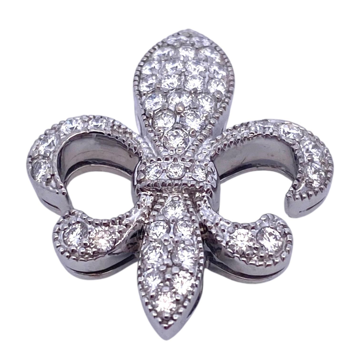 Der aus 18 Karat Weißgold gefertigte Anhänger ist mit einem Fleur-de-Lis-Motiv versehen, das mit Diamanten in Pave'-Fassung besetzt ist. Das Stück hat eine schimmernde Oberfläche mit gefrästen Rändern.
Diamanten: 1.0ctw. Farbe: F-G, Reinheit: