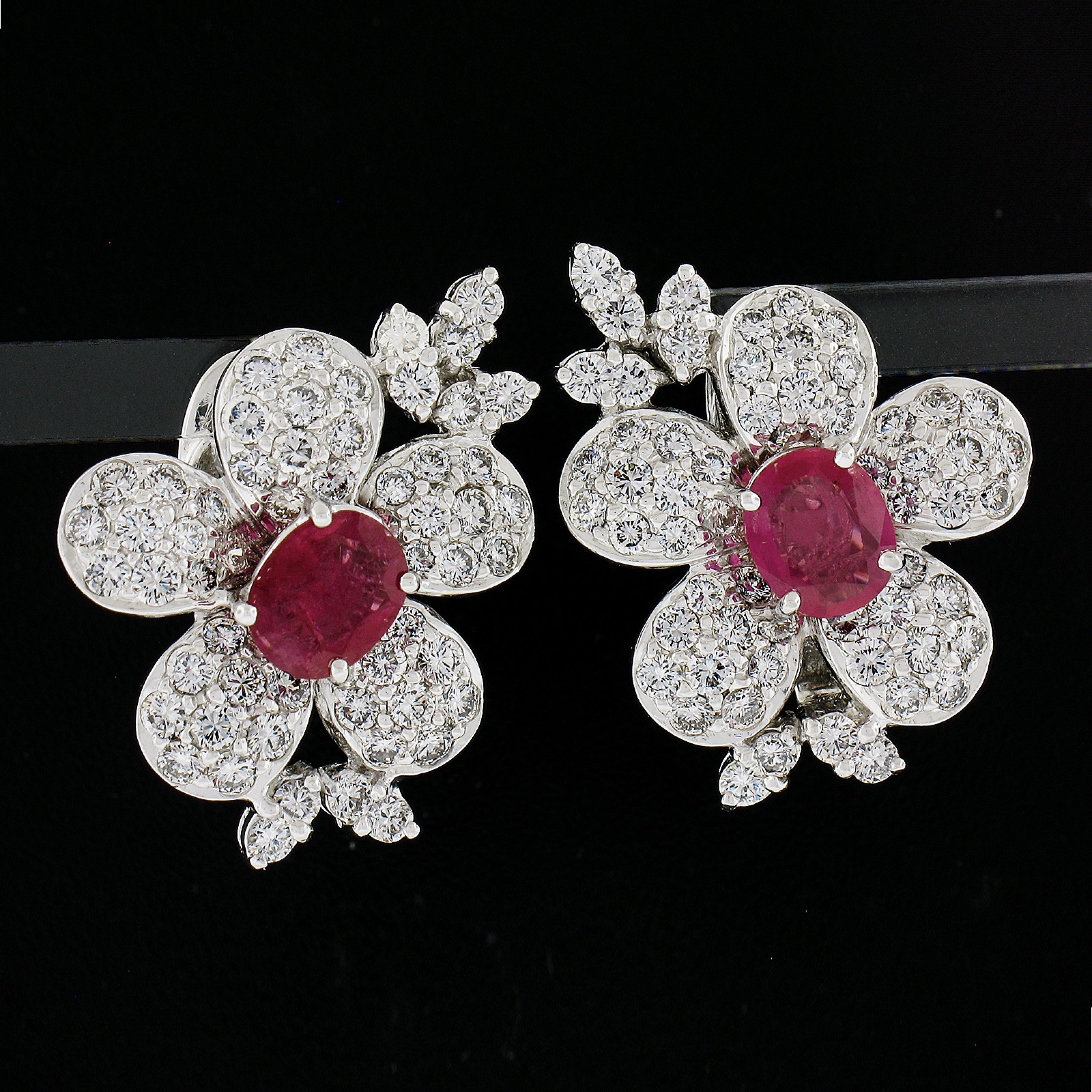 This is an absolutely magnificent pair of vintage flower statement earrings that are very well crafted in solid 18k white gold. Each earring is prong set with a very fine quality, oval brilliant cut ruby at its center. The GIA certified rubies total