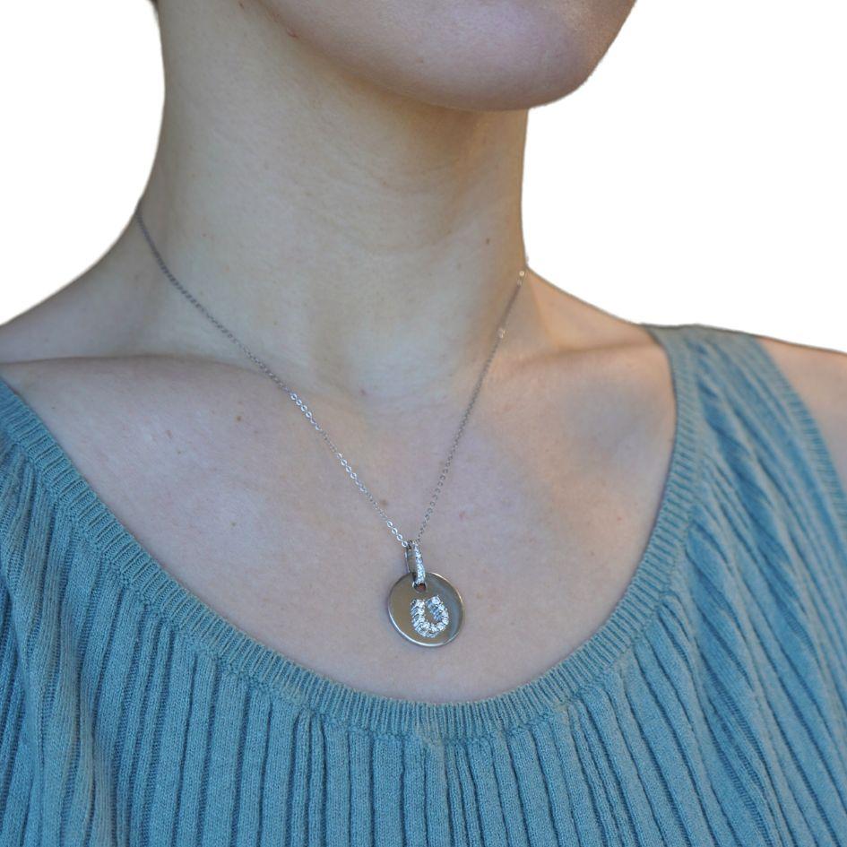 Ce collier datant des années 1980 présente un pendentif en forme de fer à cheval orné de diamants et réalisé en or blanc 18 carats, suspendu à une chaîne en or blanc 14 carats. Le pendentif rond est estampillé 