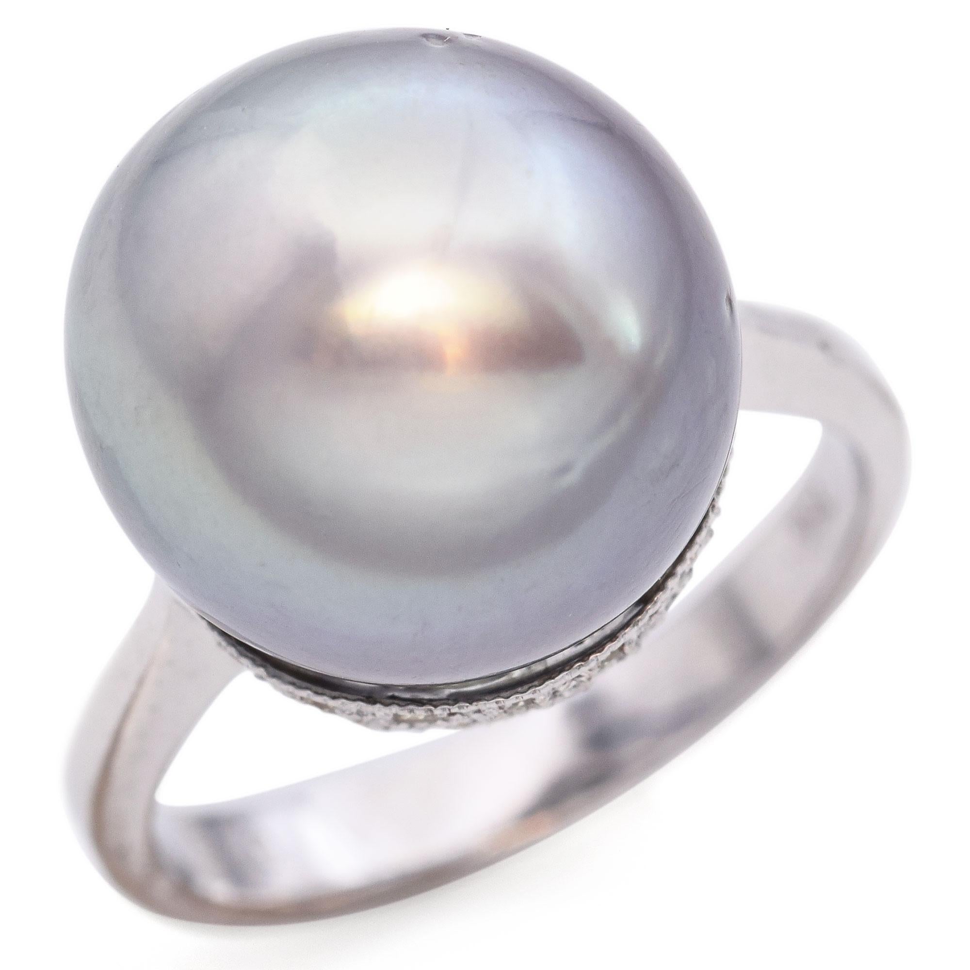 This stunning ring features a lustrous Tahitian pearl set in a sleek, minimalist band. The pearl showcases a captivating array of iridescent hues, ranging from soft grays to subtle purples, creating a mesmerizing effect. The band is crafted from