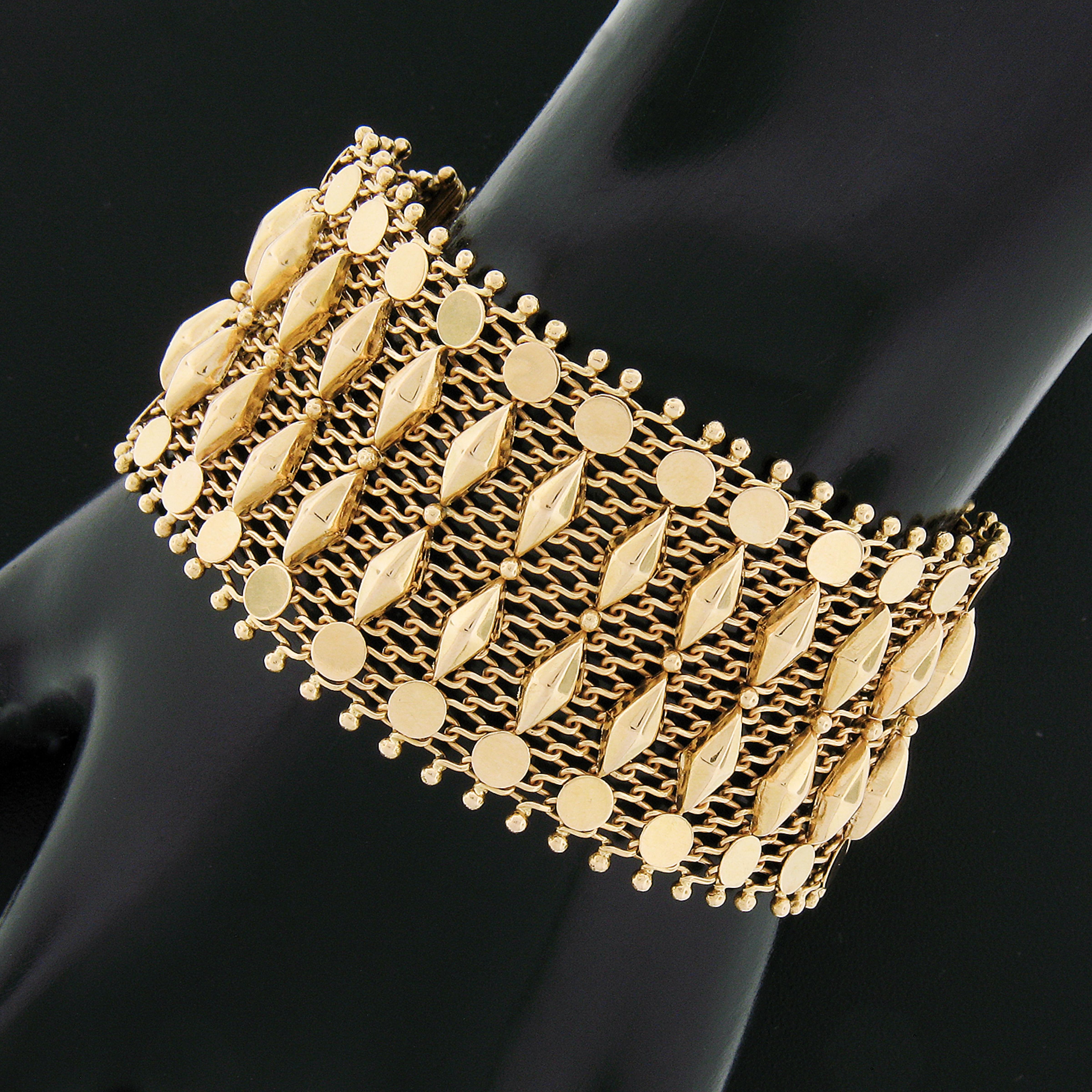 This truly elegant and unique vintage bracelet was crafted in solid 18k yellow gold and features approximately 1.3 inch wide mesh link that is silky smooth on the wrist. The bracelet is adorned with polished disks & faceted marquise shape designs