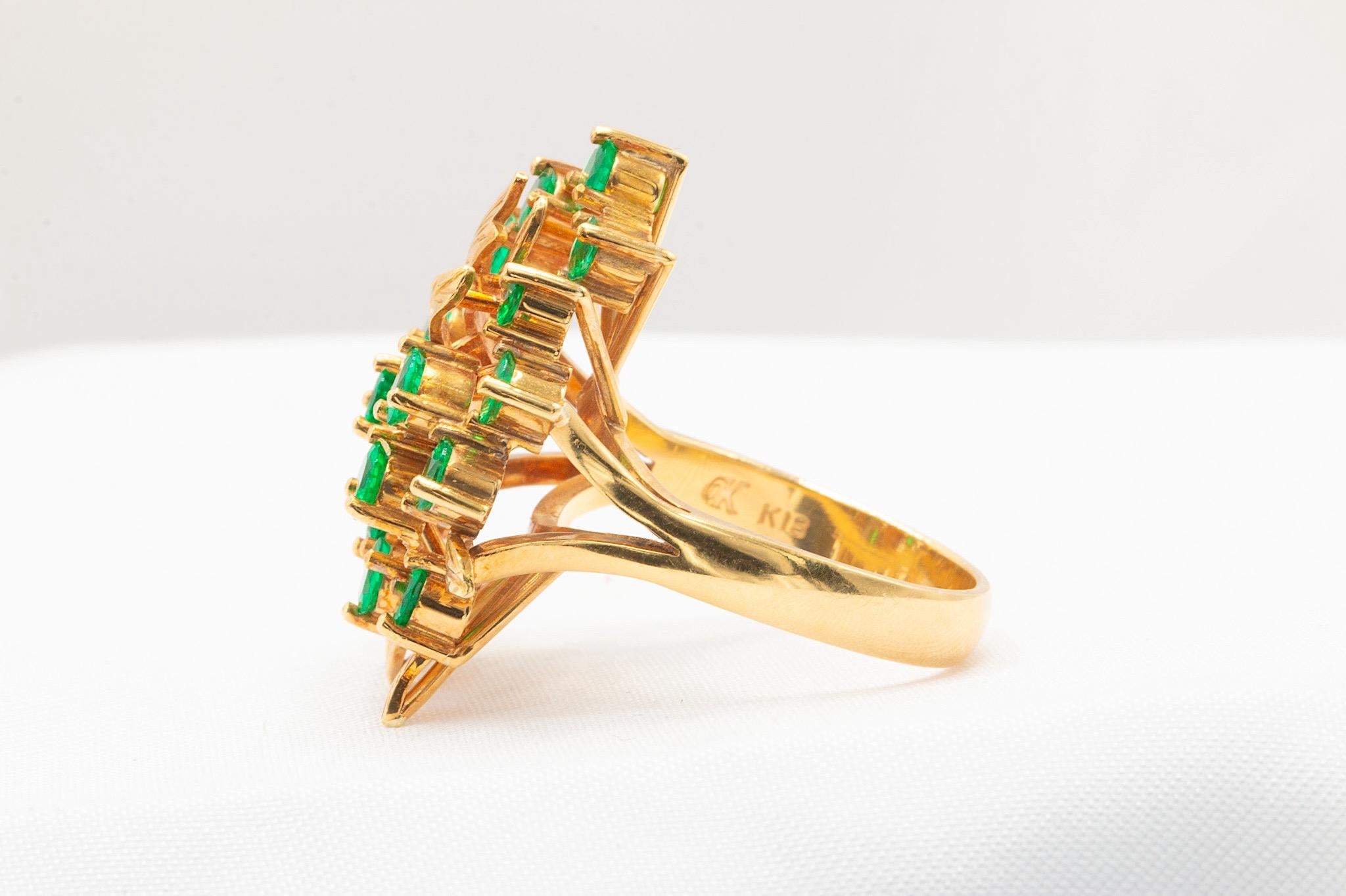Este exquisito anillo vintage está elaborado en rico oro amarillo de 18 quilates y presenta un diseño floral único adornado con 15 vibrantes y finas esmeraldas colombianas que suman aproximadamente 1,39 quilates. Una pieza atrevida y elegante, que