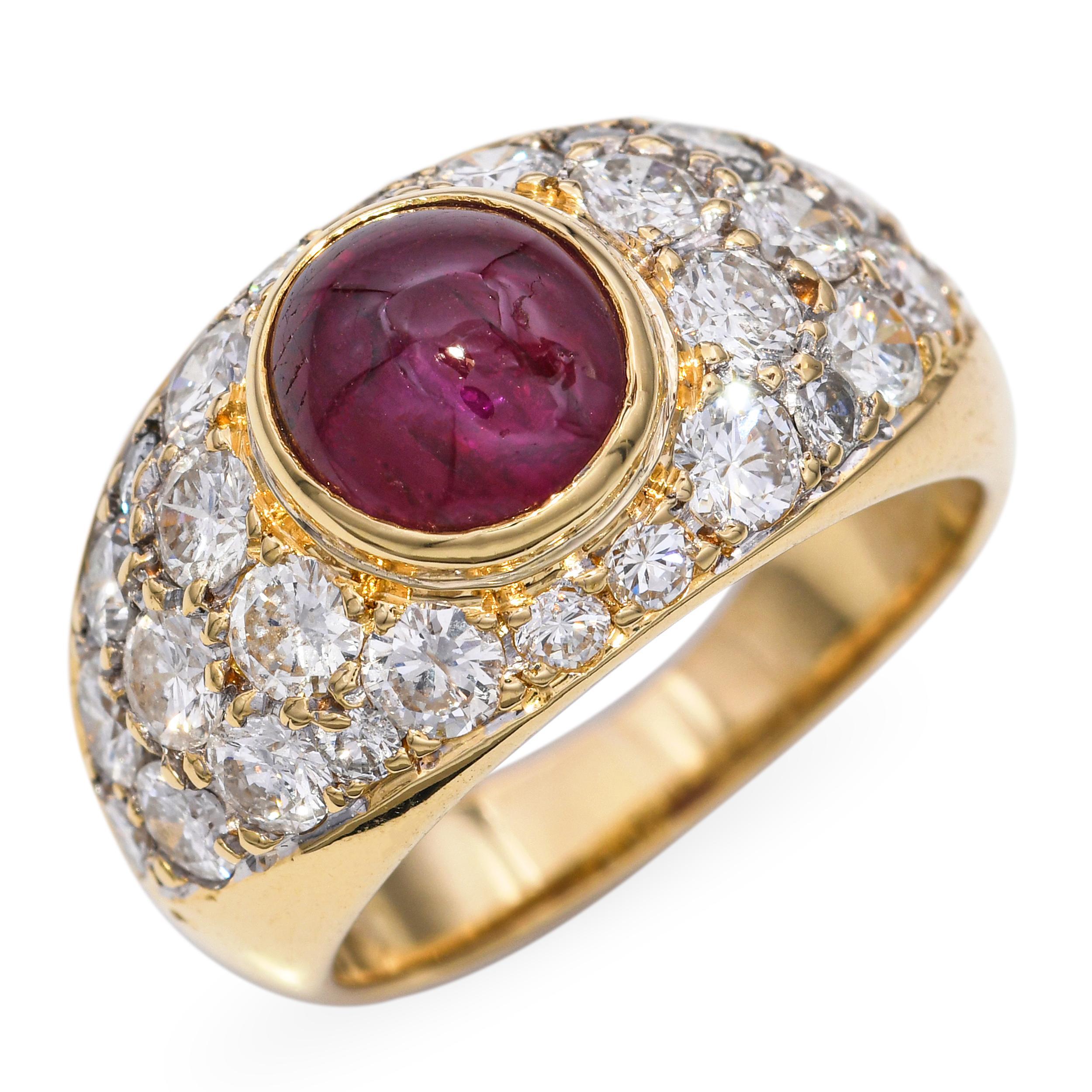 This striking vintage ring is crafted in 18k yellow gold and features a smooth, richly colored ruby cabochon as its centerpiece. Surrounding the ruby is a shimmering pavé of brilliant diamonds, adding contrast and luxurious sparkle. The warm gold