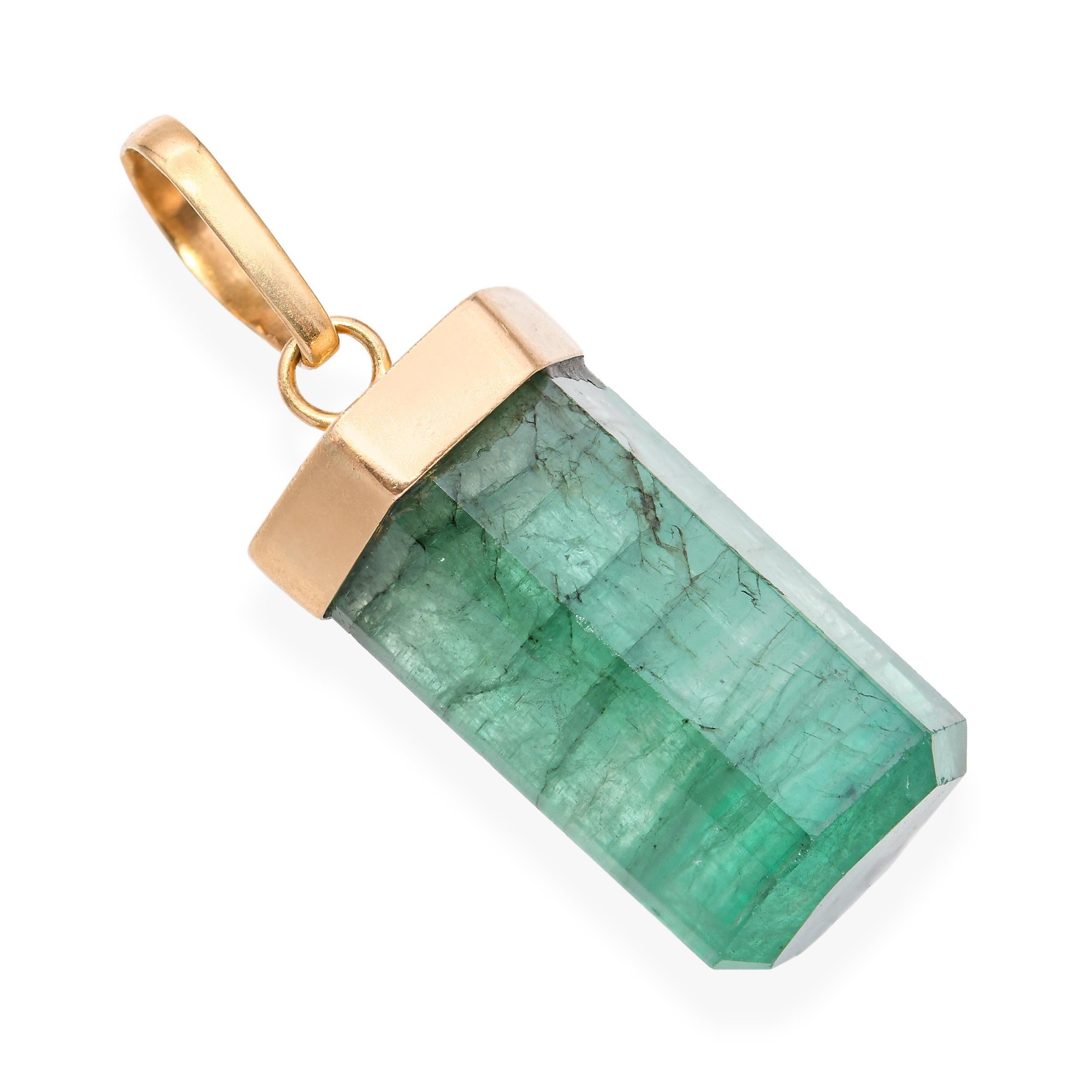 Ce pendentif vintage en or jaune 18 carats est orné d'une magnifique émeraude de 22,5 carats, conservée dans une forme de cristal brut poli qui met en valeur sa structure et son caractère naturels. La pierre présente un zonage de couleur visible, ce