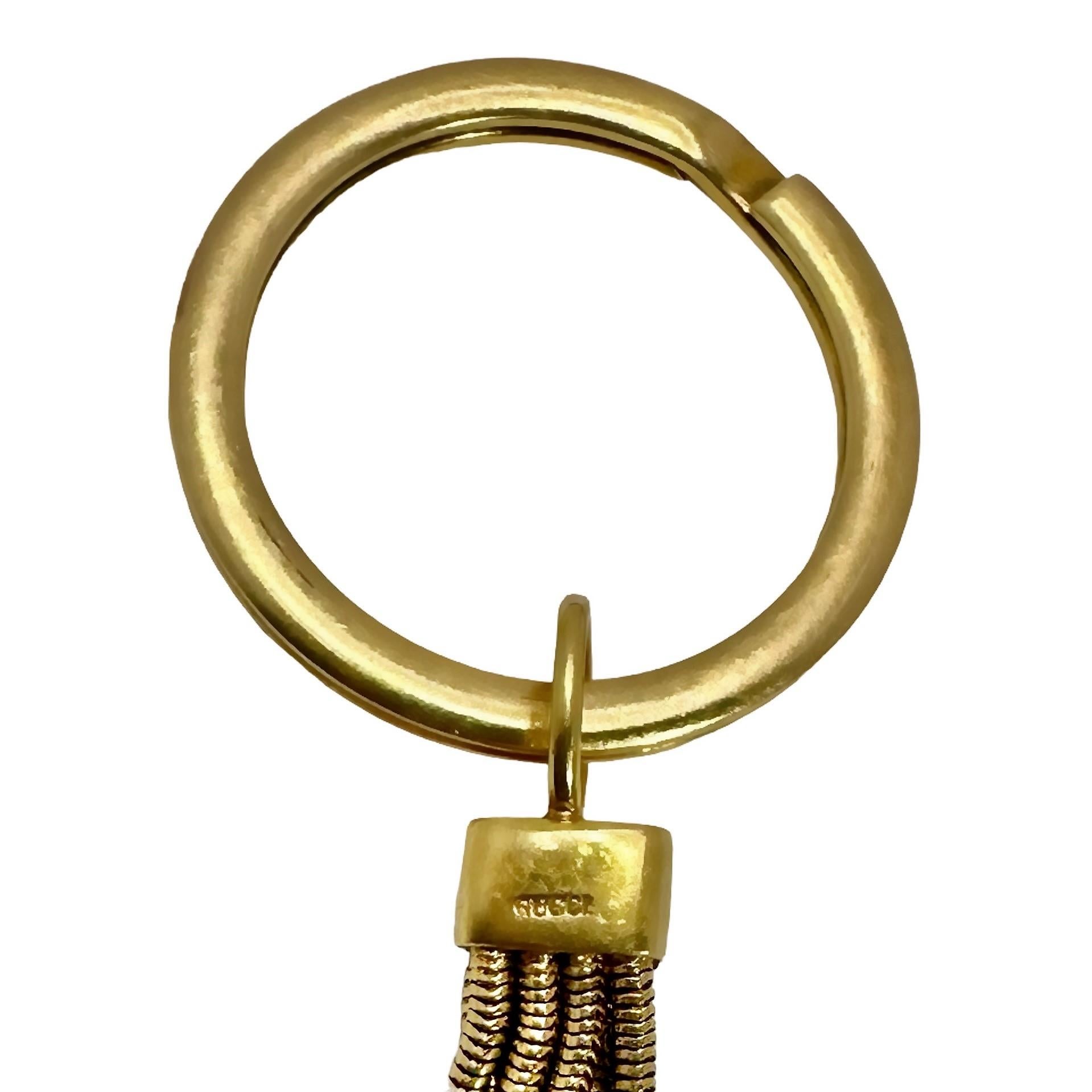 This imaginative Mid-20th Century Gucci key chain consists of a large gold key ring from which is suspended a length of round Cobra Link chain holding a large natural rock crystal, frosted, reptilian pattern heart. The heart measures almost 1 3/8