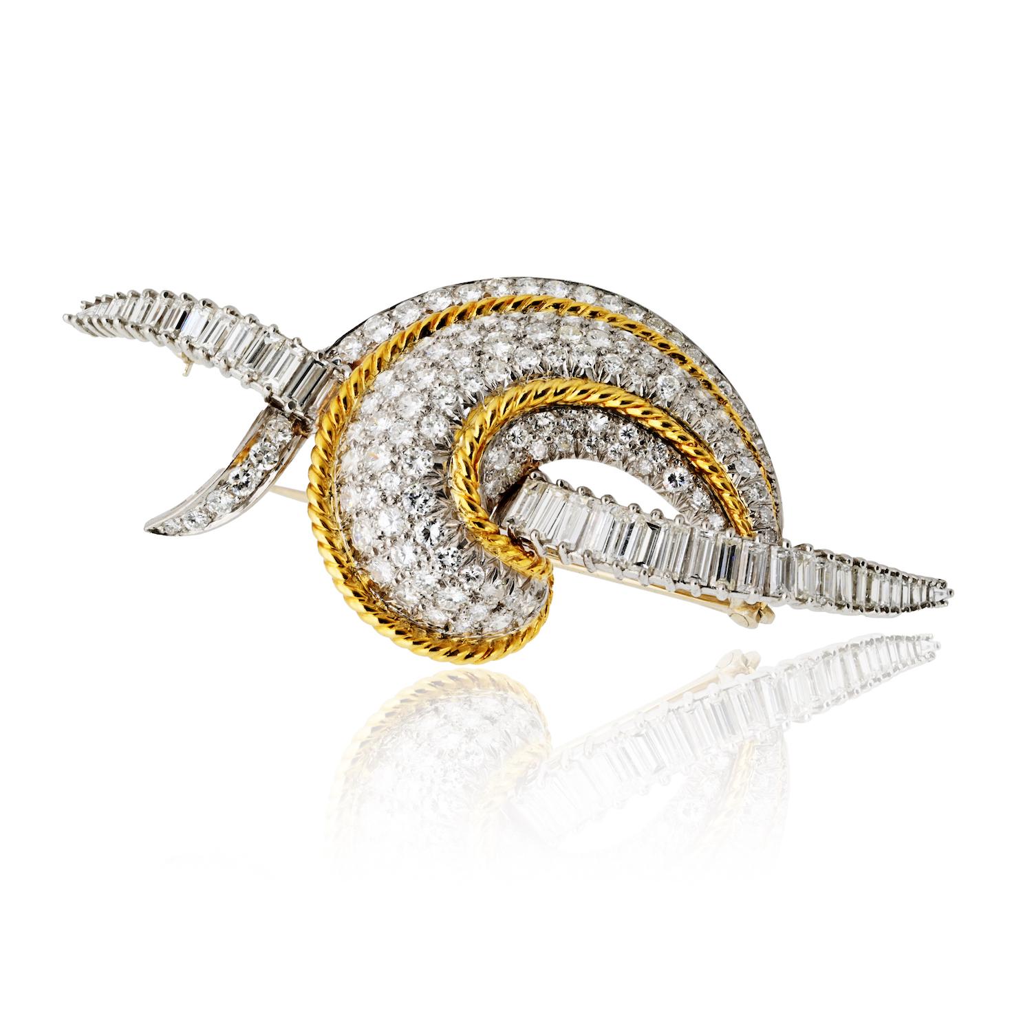 Questa spilla con diamante risale agli anni '70 ed è realizzata con maestria in una combinazione di platino e oro giallo 18 carati. Disegnato con un elegante motivo a volute, è impreziosito da un'abbagliante serie di circa 8,00 carati di diamanti