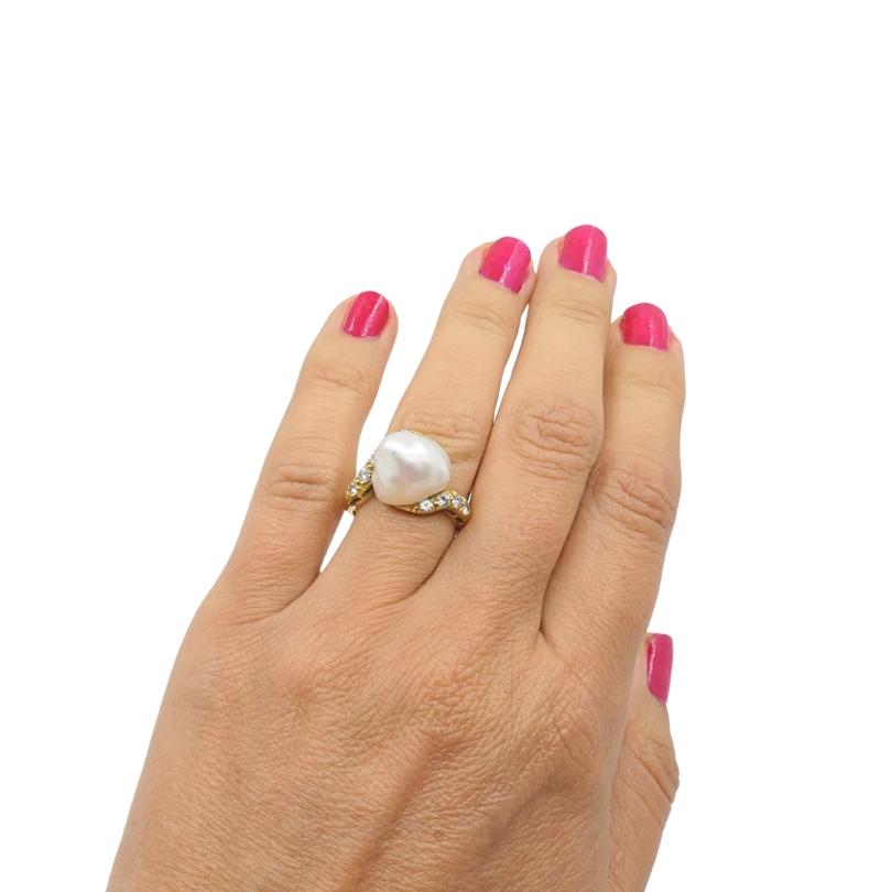 Questo anello vintage in oro giallo 18 carati è caratterizzato da un'audace perla barocca accentata da  diamanti in un design bypass asimmetrico. La perla centrale misura circa 7/16 di pollice di altezza, ergendosi in modo evidente sopra il dito per