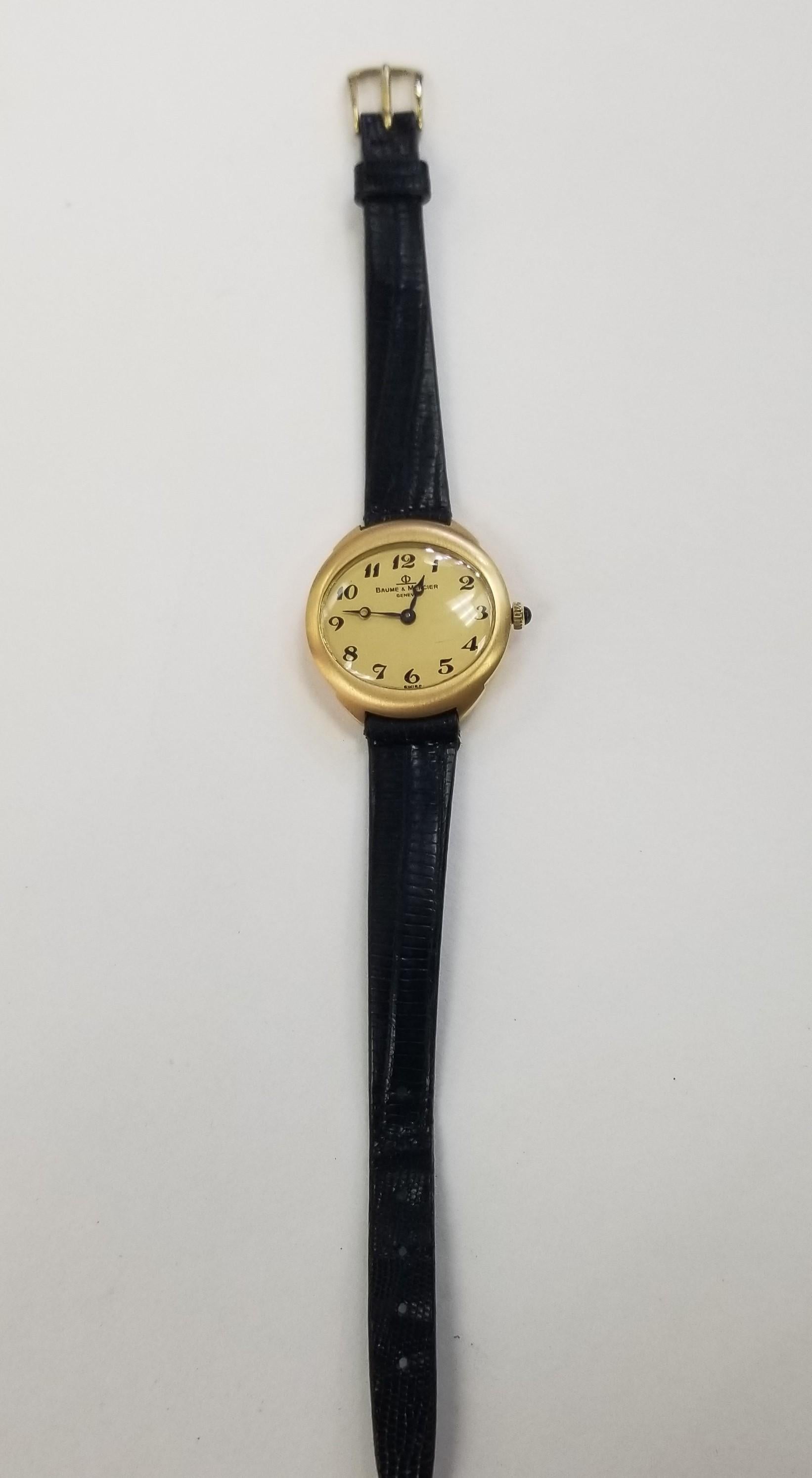 A 27mm yellow gold Ladies Baume & Mercier wristwatch. Featuring a stunning a gold dial with Arabic numbers. The watch is fitted with a sapphire glass, movement and a Baume & Mercier black leather strap. 

This timepiece comes with our own