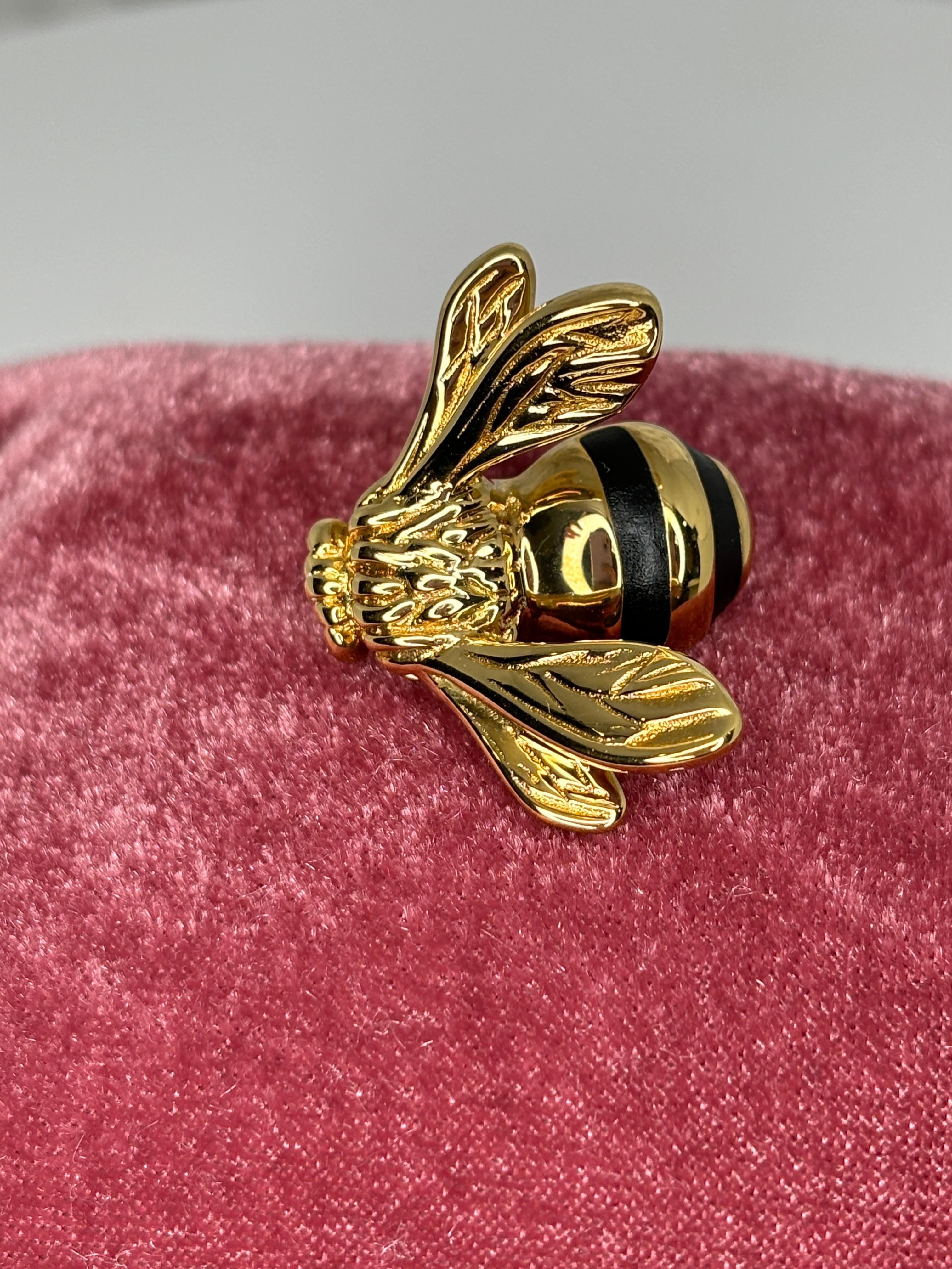 Precioso broche de abeja de oro amarillo pulido de 18 quilates. Este broche único muestra atención al detalle y está decorado con esmalte negro. El contraste entre el oro brillante y el esmalte negro hace que destaque. Esta pieza es perfecta para