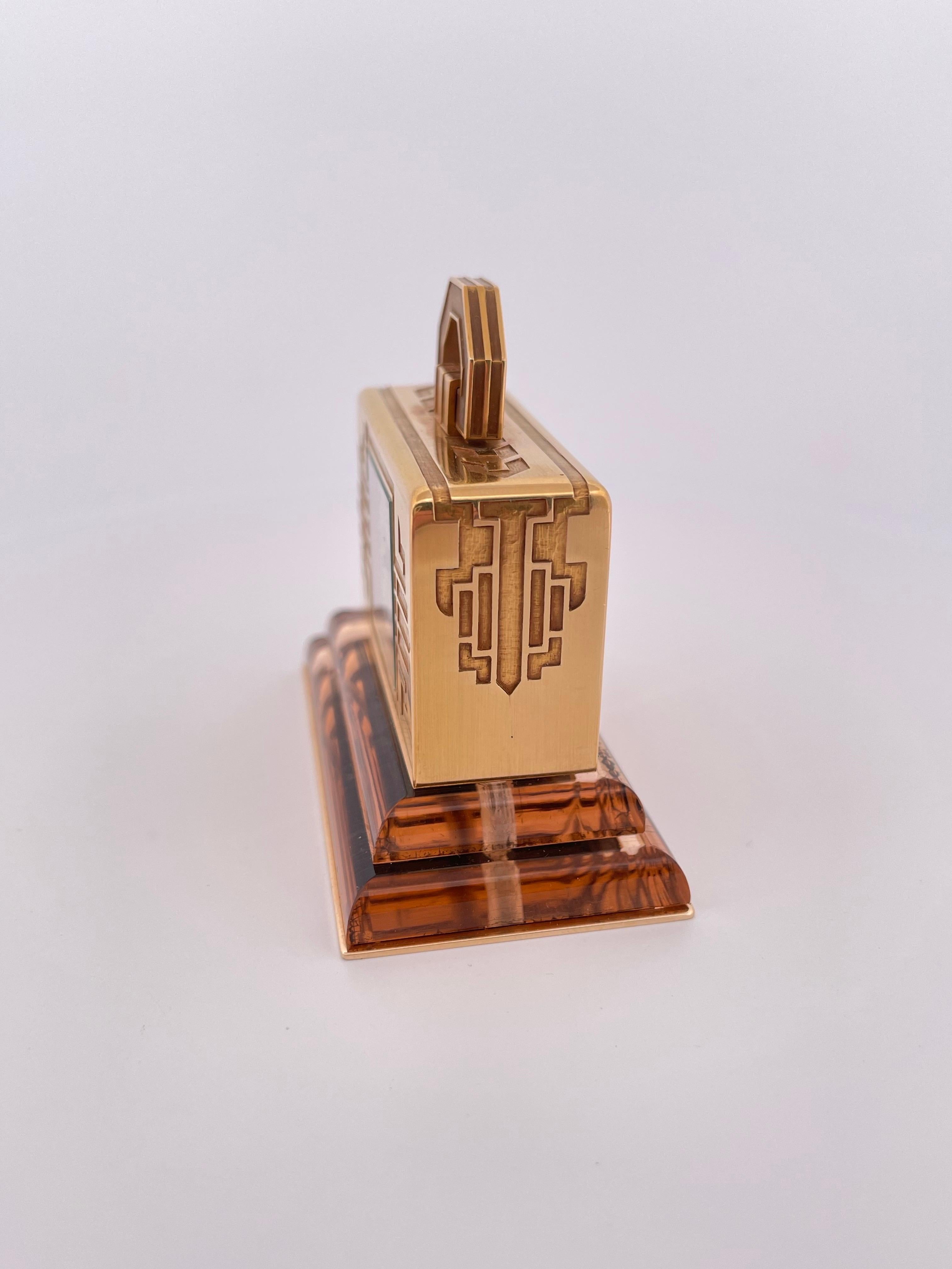 This rare Cartier 18k gold Art Deco travel clock embodies luxury, craftsmanship, and architectural elegance. Crafted in rich yellow gold, the clock features bold geometric motifs and a hinged handle reminiscent of a miniature handbag—an iconic nod