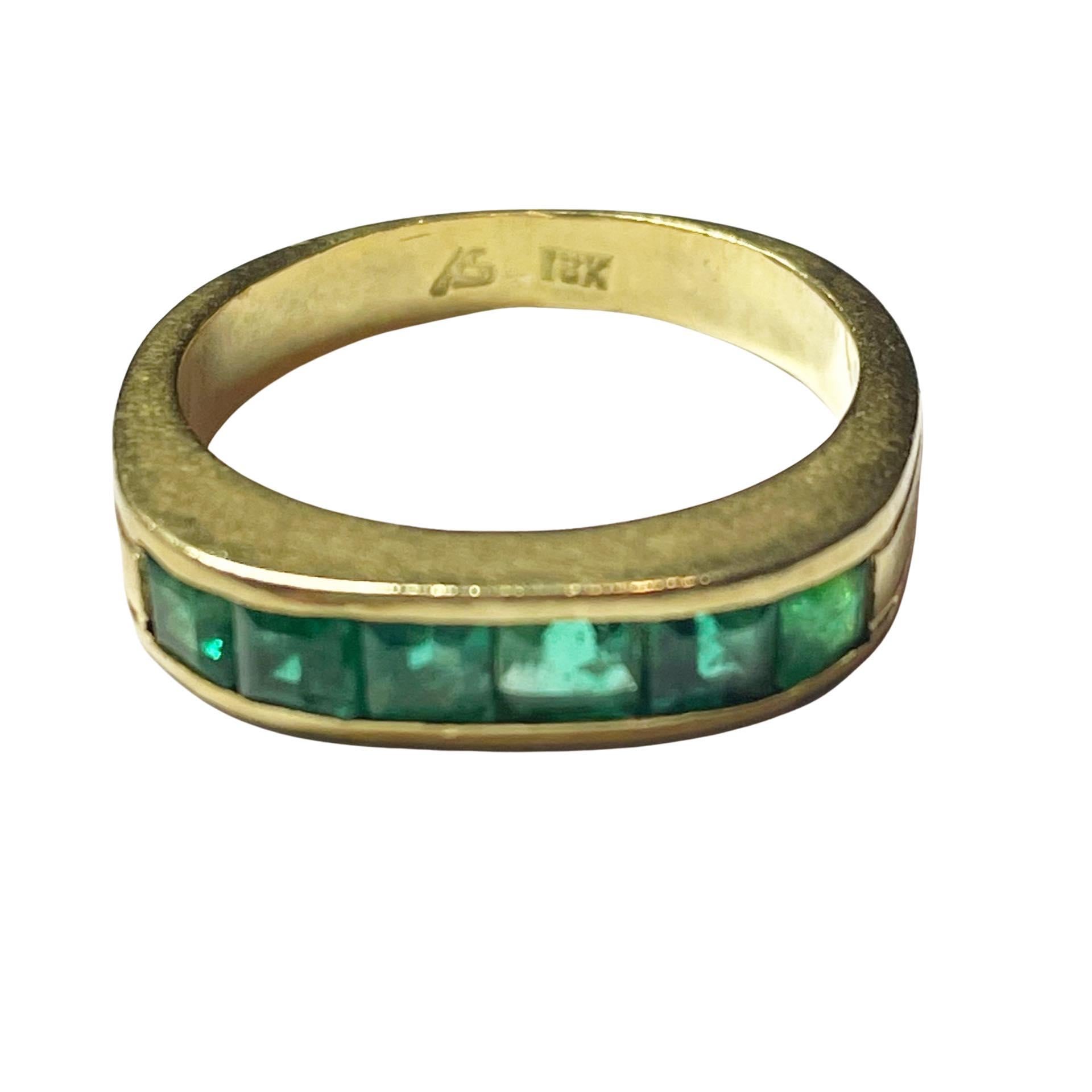 These beautiful green gems are Mays birthstone, set in an 18K yellow gold channel the straight shank design is delicately accented by two carved lines outlining the band.  This bands minimalist design is suitable for men or woman, worn alone,