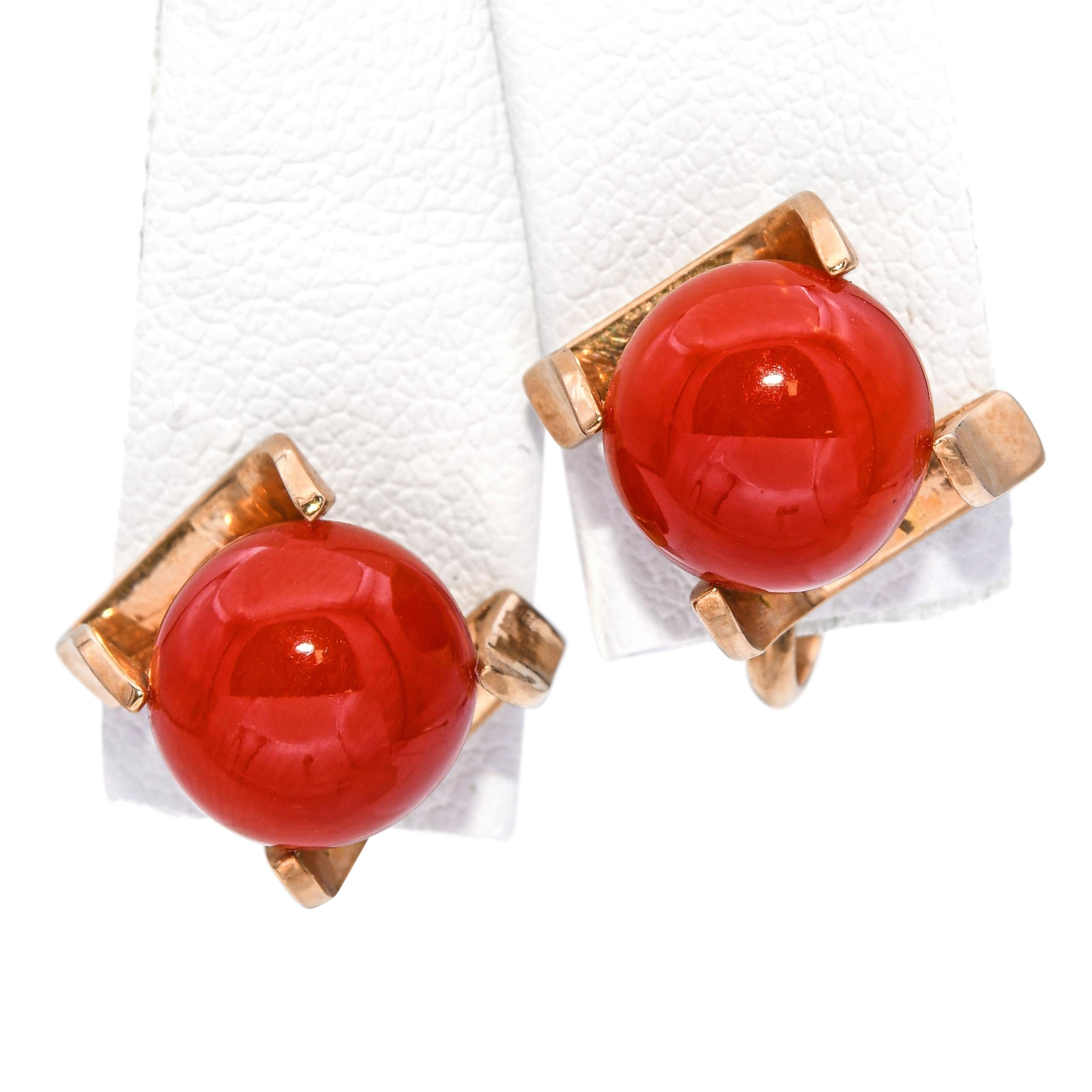 Questi straordinari orecchini vintage sono realizzati in oro giallo 18 carati e presentano vibranti cabochon di corallo rosso saldamente incastonati in audaci montature a quattro punte. La ricca tonalità e la levigatezza del corallo contrastano