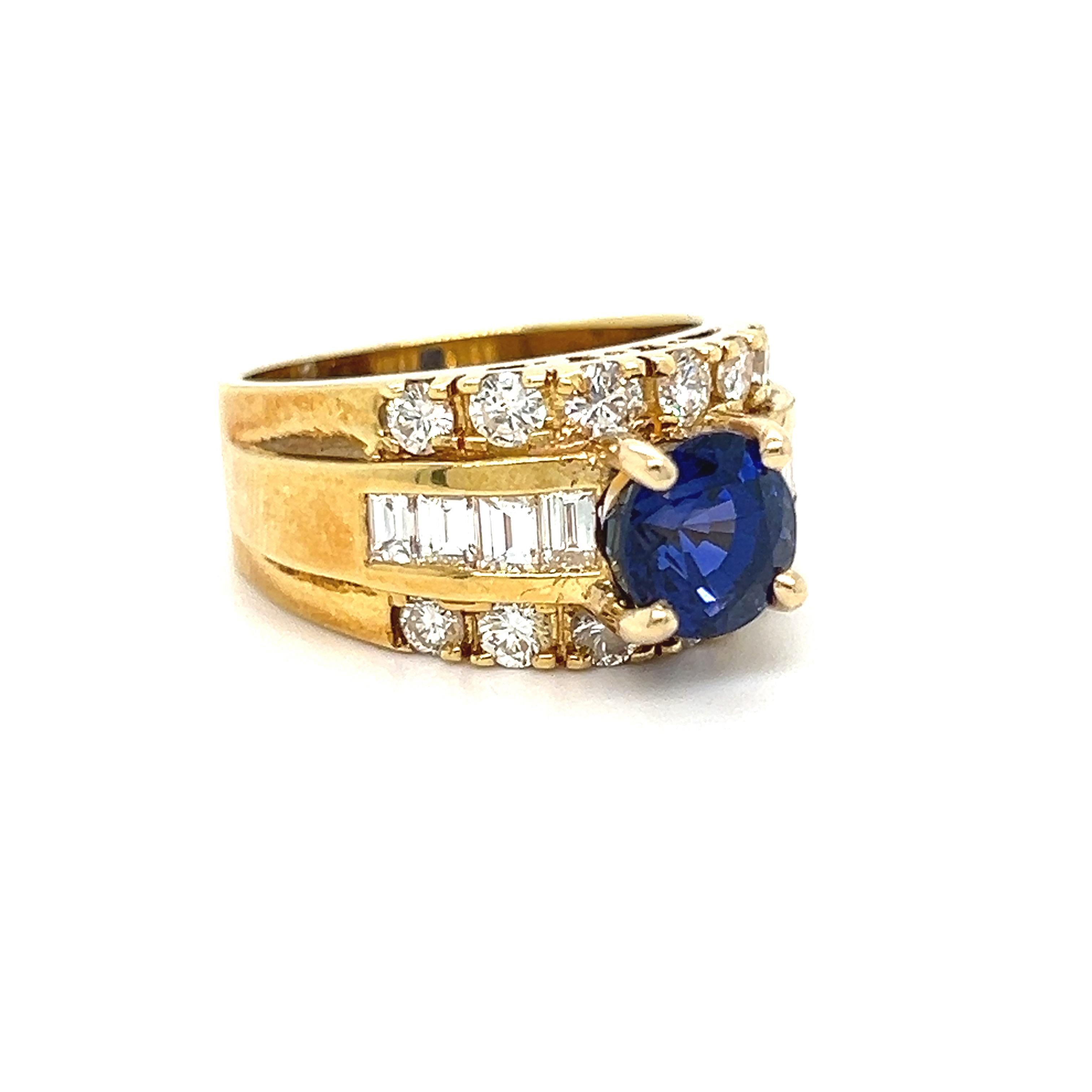 This Vintage Diamond and Sapphire Ring is such a unique, beautiful design - with a truly stopping centerstone! Crafted in 18K Yellow Gold, the design features a central Round Sapphire, flanked by both Round and Baguette Cut Diamonds! In the center,