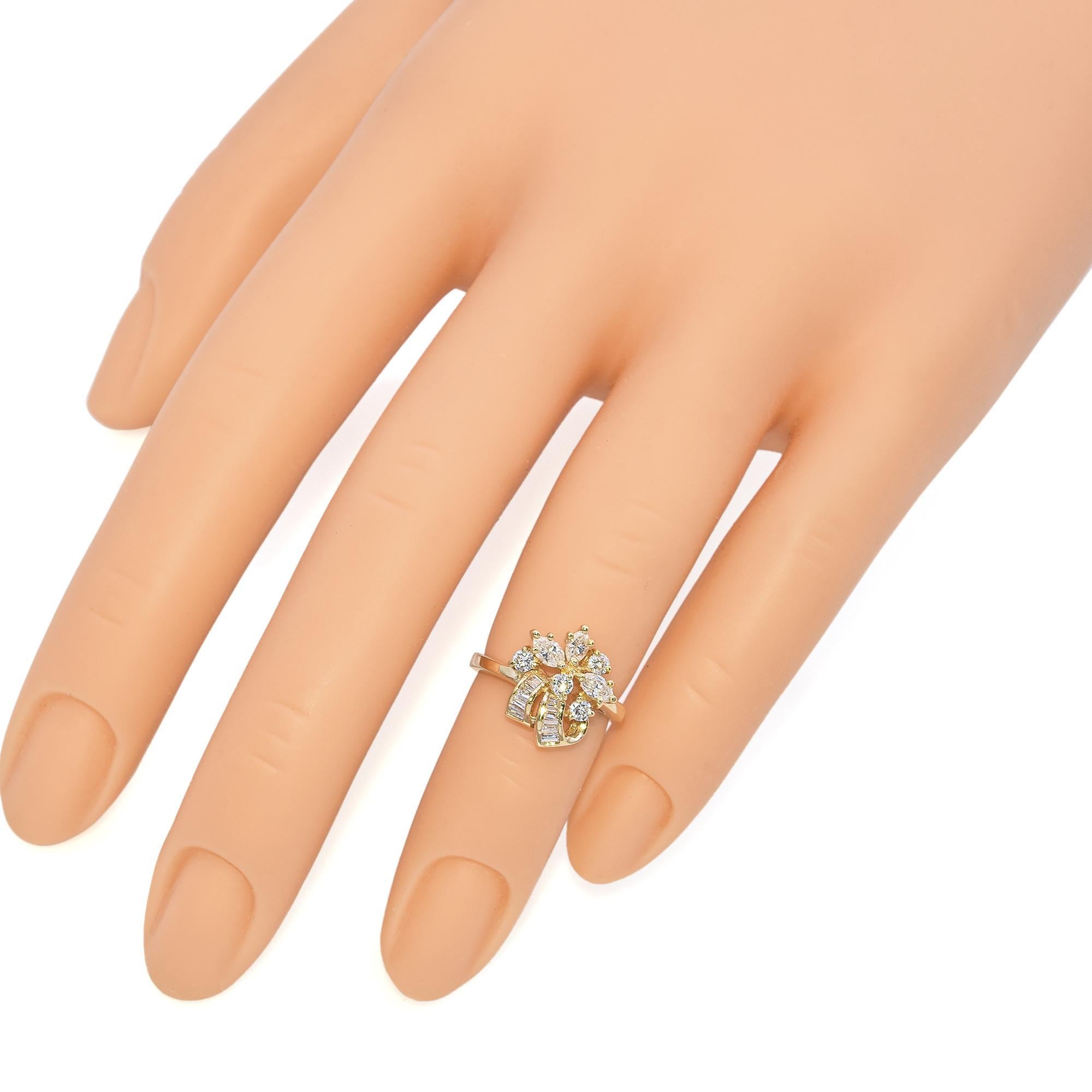 his exquisite ring is crafted in gold. The design features a stunning cluster of round and marquise-cut diamonds, arranged in a floral pattern. The diamonds are set in a prong setting, enhancing their brilliance. Below the cluster, baguette-cut