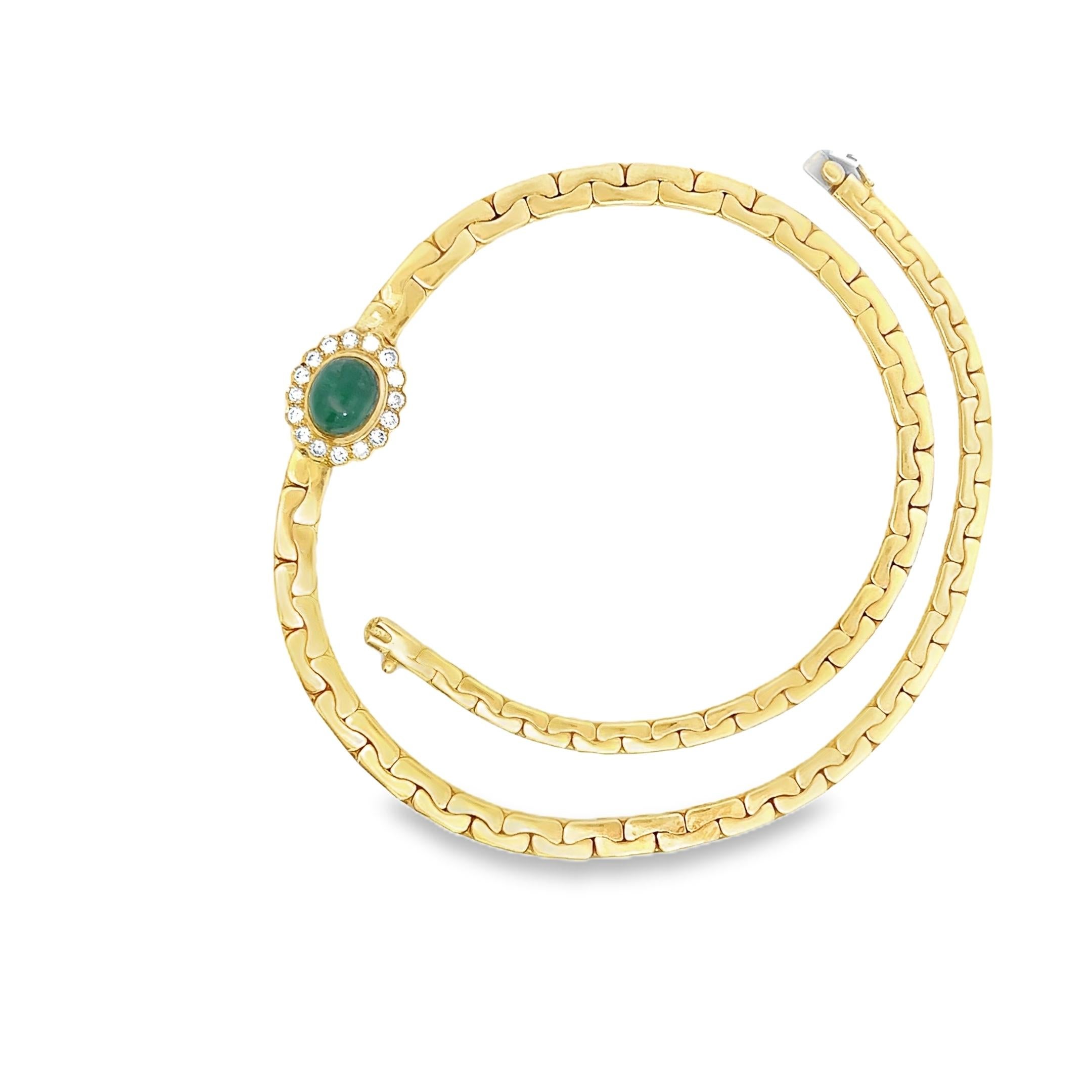 This Vintage Retro Diamond and Emerald Pendant Chain Necklace is crafted in 18-karat yellow gold and features a striking green oval cabochon emerald at its center. The emerald is surrounded by a bezel-set halo of 16 round brilliant-cut white