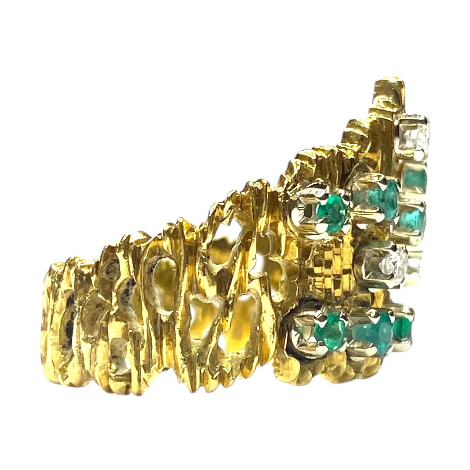 Crafted in 18K yellow gold, the ring showcases a textured design with a striking arrangement of round green emeralds and brilliant white diamonds. 
The intricate setting highlights the vibrant contrast between the stones. 
The emeralds, totaling 0.3
