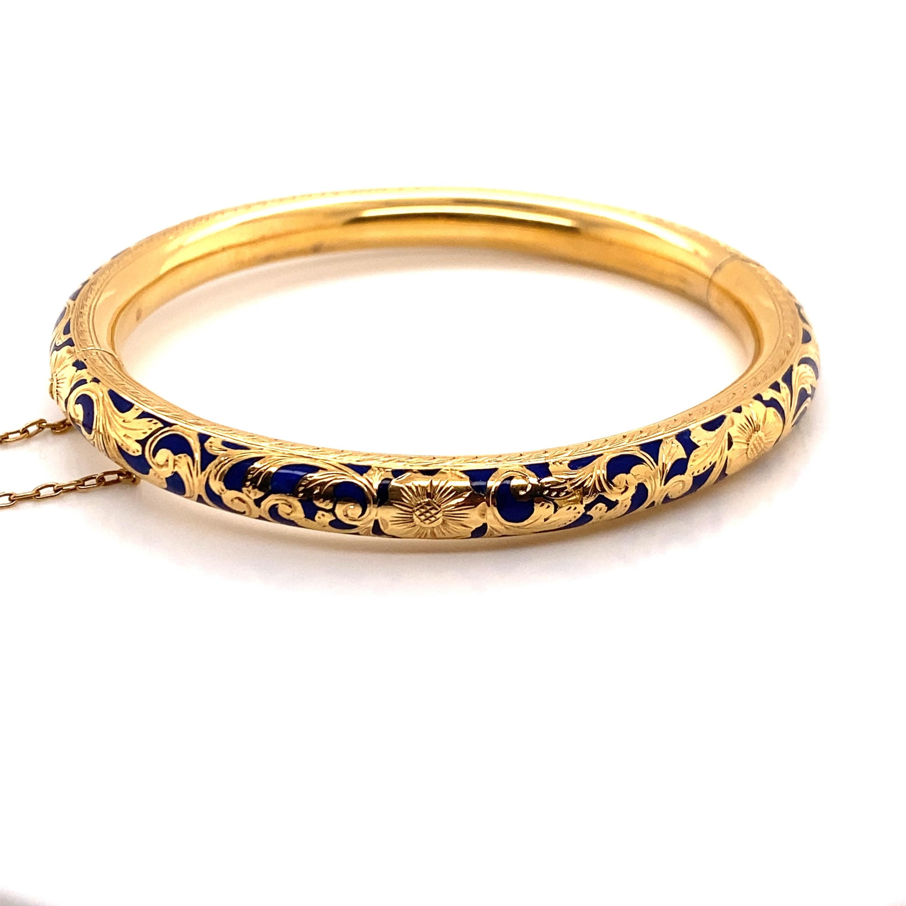 Vintage 18K Yellow Gold Floral Bangle with Blue Enamel. The color of the enamel is cobalt blue and the gold flowers and leaves are engraved. The bangle is 7.2mm wide and 6.8mm high off the wrist. The inside diameter is 2.2 inches high and 2.4 inches