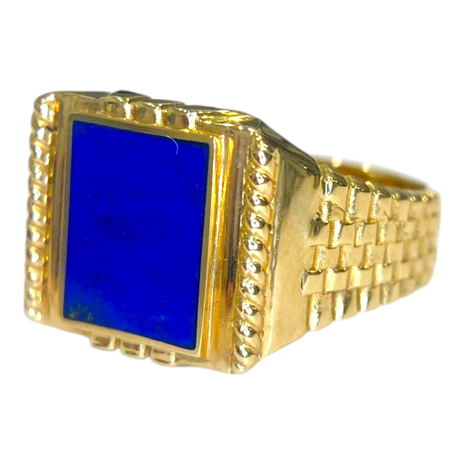 Anello con sigillo d'epoca in oro giallo 18 carati, caratterizzato da un audace design rettangolare con un intarsio di lapislazzuli blu intenso. La fascia presenta dettagli intricati lungo i lati, che mettono in risalto lo smalto