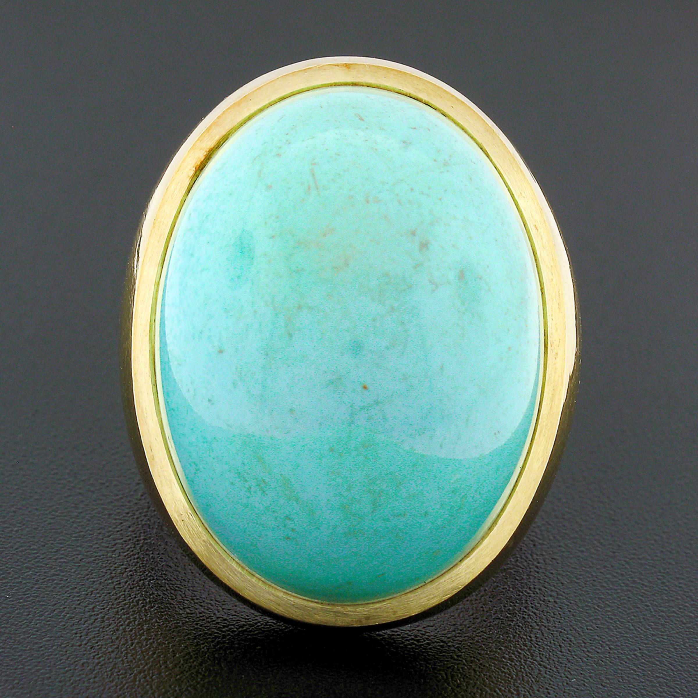 This magnificent vintage ring is crafted in solid 18k yellow gold and features a large oval cabochon cut turquoise neatly bezel set at its center. This fine stone displays an absolutely gorgeous light robins egg color that brings a super attractive