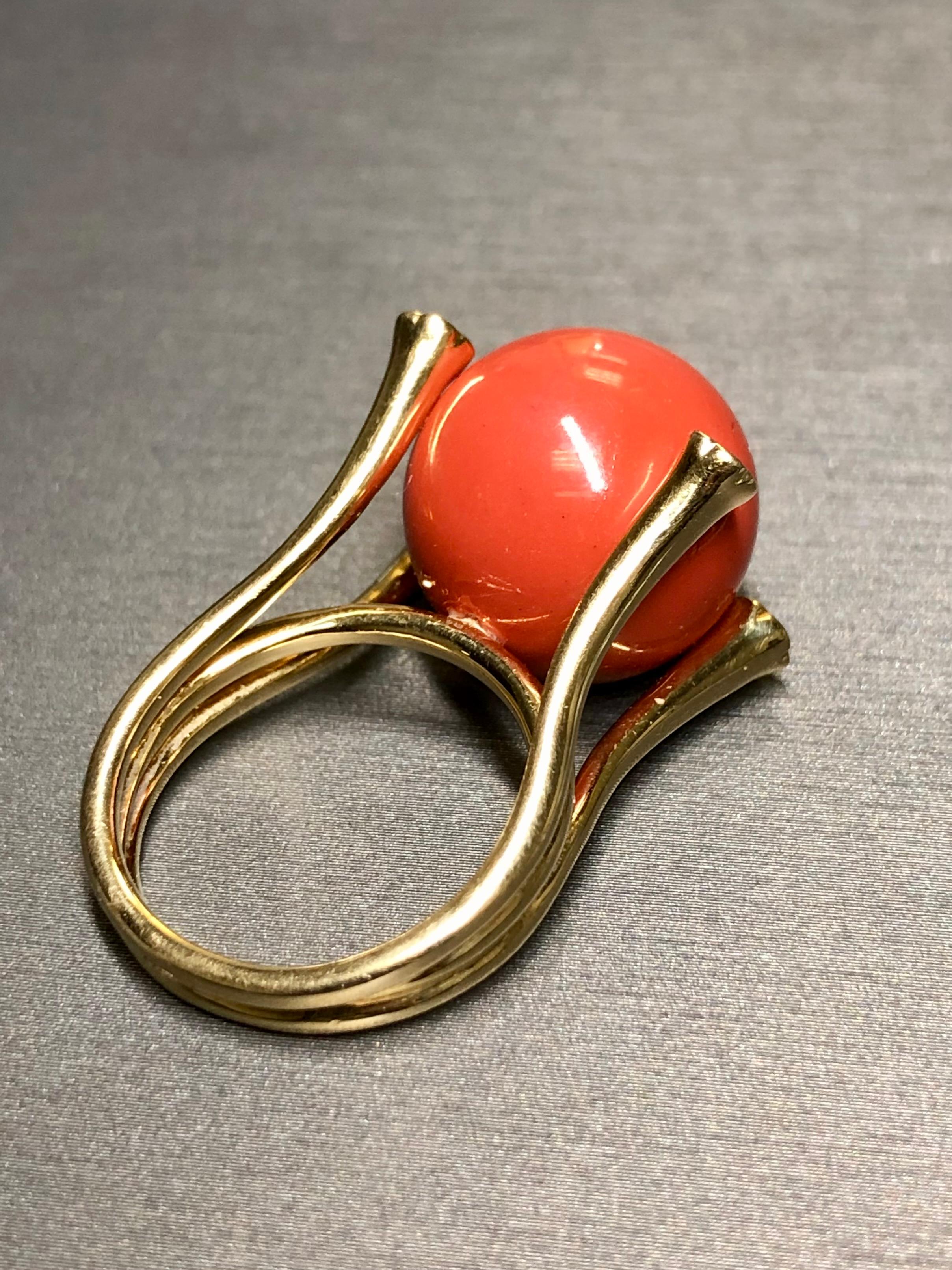 
A bold and stately cocktail ring crafted in very solid 18K yellow gold and centered by a large natural sphere of red coral measuring 15.76mm in diameter. The setting also contains .04cttw in flush set diamonds on all four prongs holding the coral.