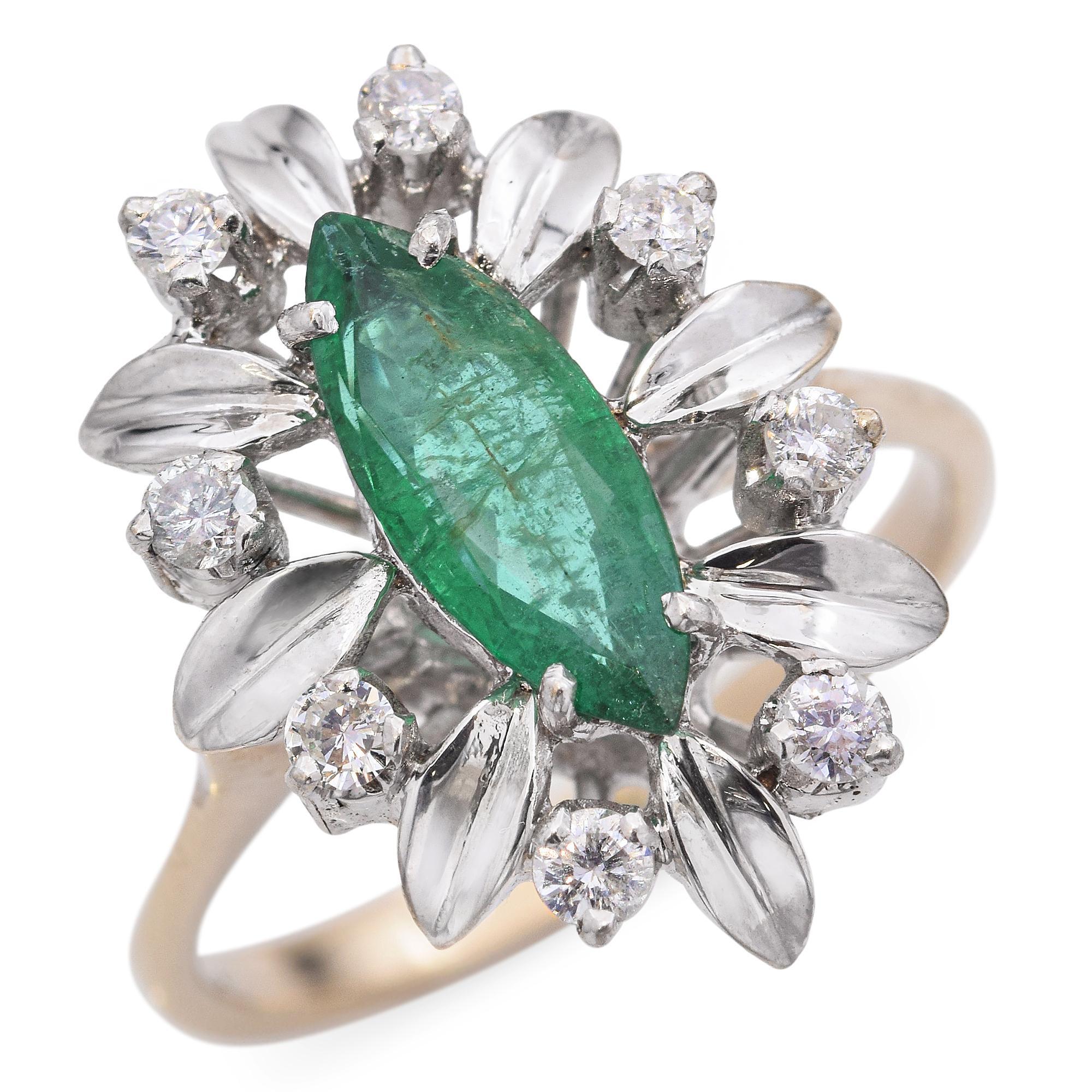 This vintage ring showcases a striking marquise-cut emerald at its center, surrounded by a halo of round brilliant diamonds and elongated silver-toned accents. The intricate design creates a floral motif, enhancing the vibrant green of the