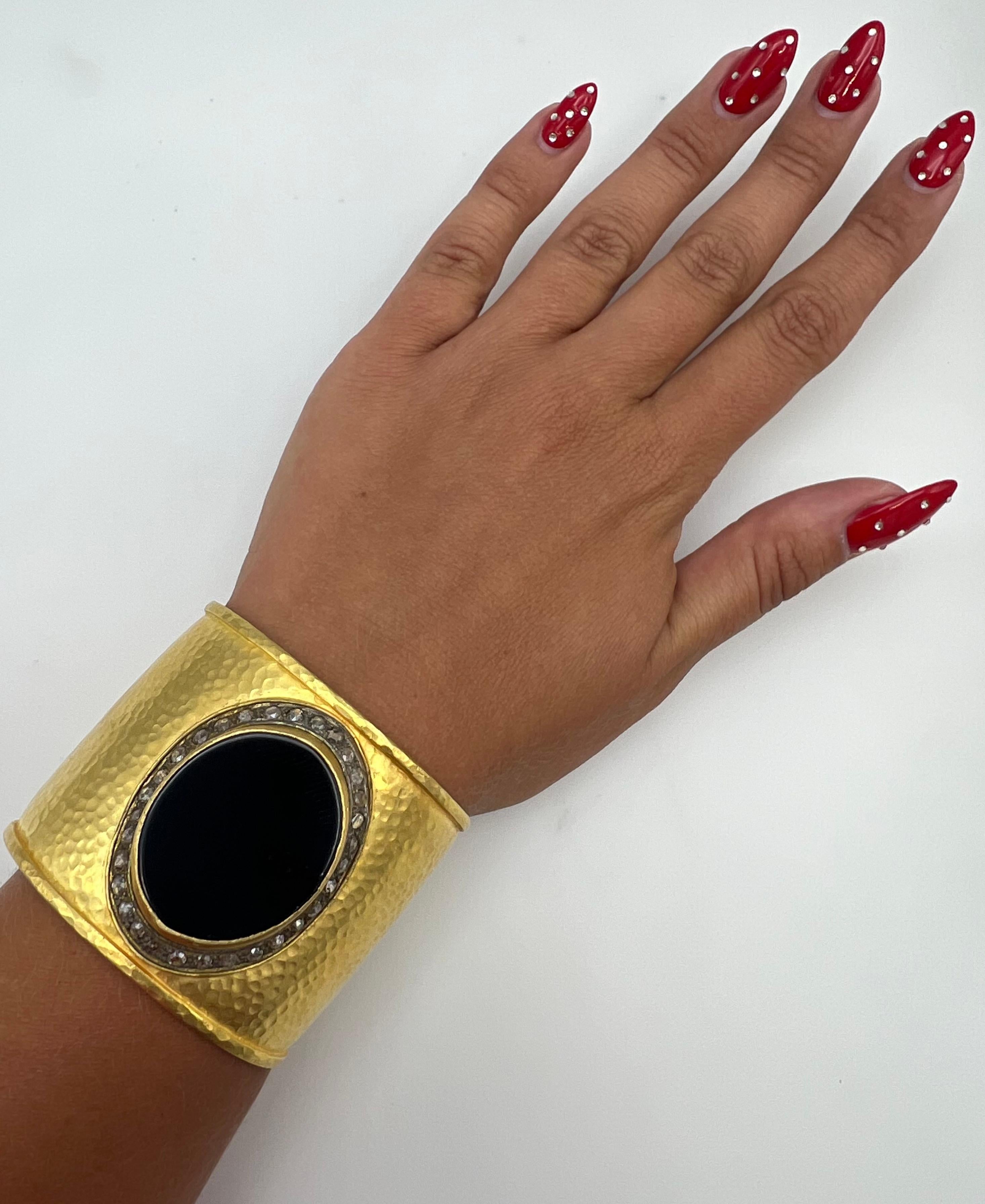 The bracelet features black oval onyx on the front, accented with rose cut diamonds around it and 18 karat yellow gold with hammered finish.
Total. Weight is 74.6 grams.
Measurments: 2 inches high and 6 inches inner circumference. 