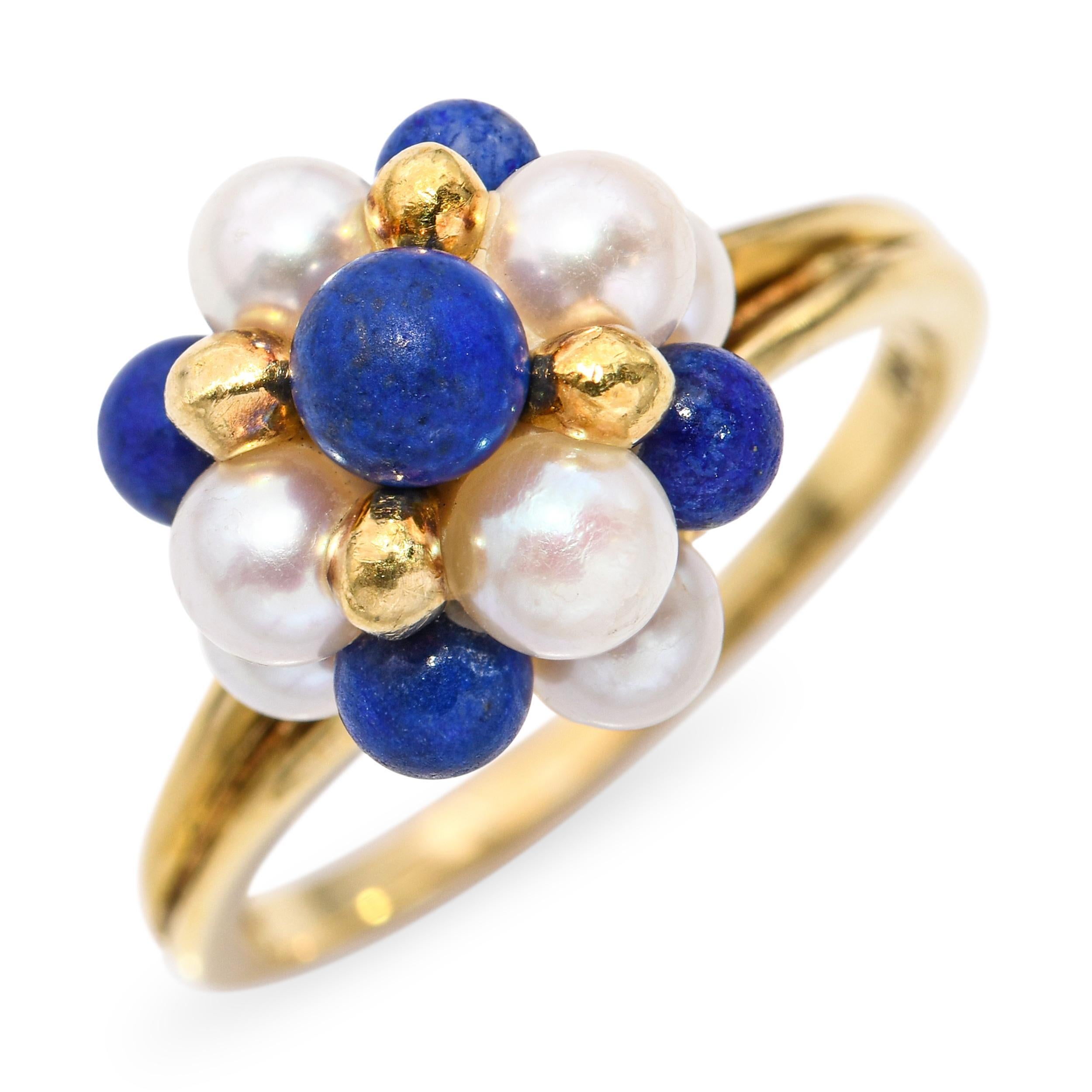 This elegant vintage ring is crafted in 18K yellow gold and features a charming cluster design of luminous white pearls and rich royal-blue lapis lazuli cabochons. The gems are arranged in a domed floral composition accented by polished gold beads,