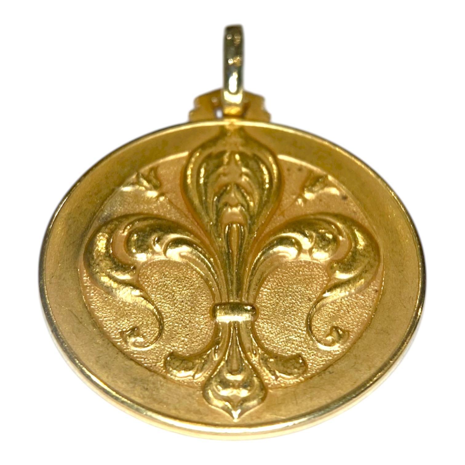 Pendentif disque italien vintage en or jaune 18 carats. Le design présente un motif de fleur de lys orné, mettant en valeur des courbes élégantes avec une finition polie et texturée.
Dimensions : 34.0 mm L (y compris la bague) x 25.0 mm L 
Poids :
