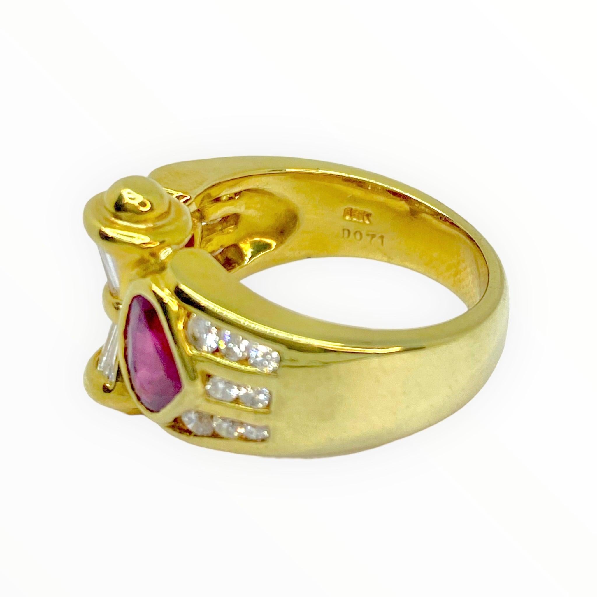 Crafted in 18K yellow gold, the ring features two pear shape rubies on the front with a scroll motif in the center. The scroll is set with tapered baguette cut diamonds and accented with a gold bead on top and bottom. Diamond set graduating