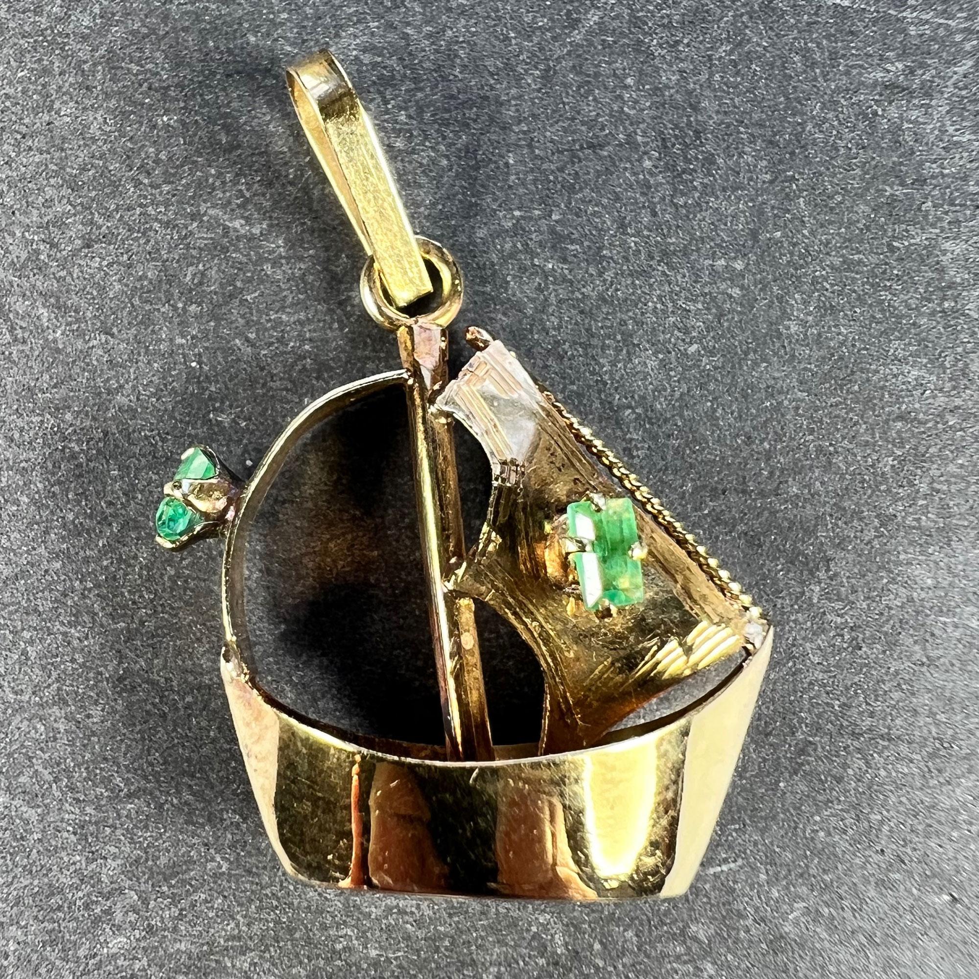 An 18 karat (18K) yellow gold charm pendant designed as a sailing yacht or boat. Set with two natural emerald-cut emeralds to the sails. Stamped 18K to the base for 18 karat gold.

Total gem weight: approximately 0.10 carats
Dimensions: 2 x 1.9 x