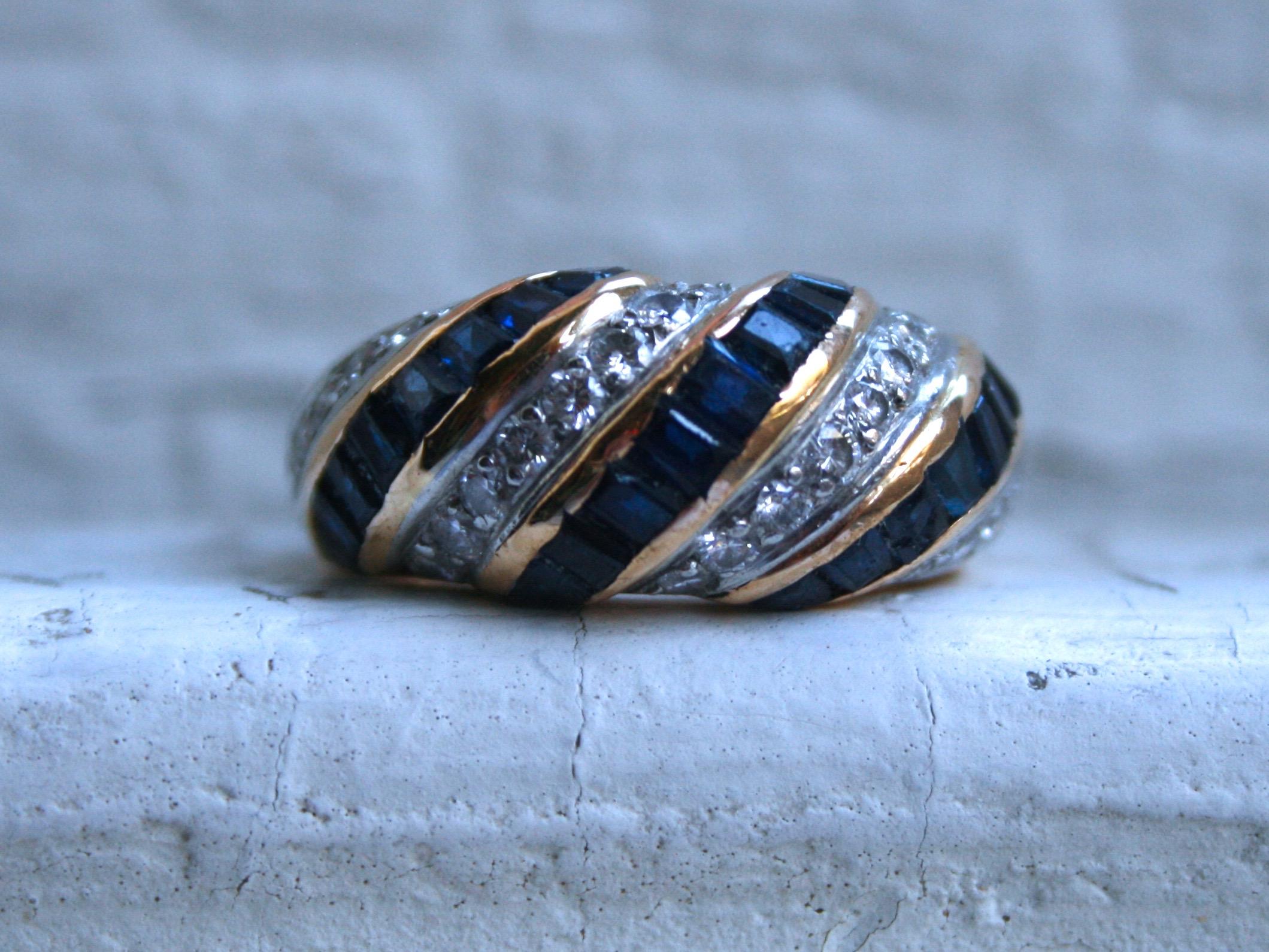 This Vintage Channel Sapphire and Diamond Wedding Band is a gorgeous classic, made by a company well know for it's excellence in craftsmanship! Crafted in 18K Yellow Gold, the band features alternating twists of beautiful Channel Set Square Cut