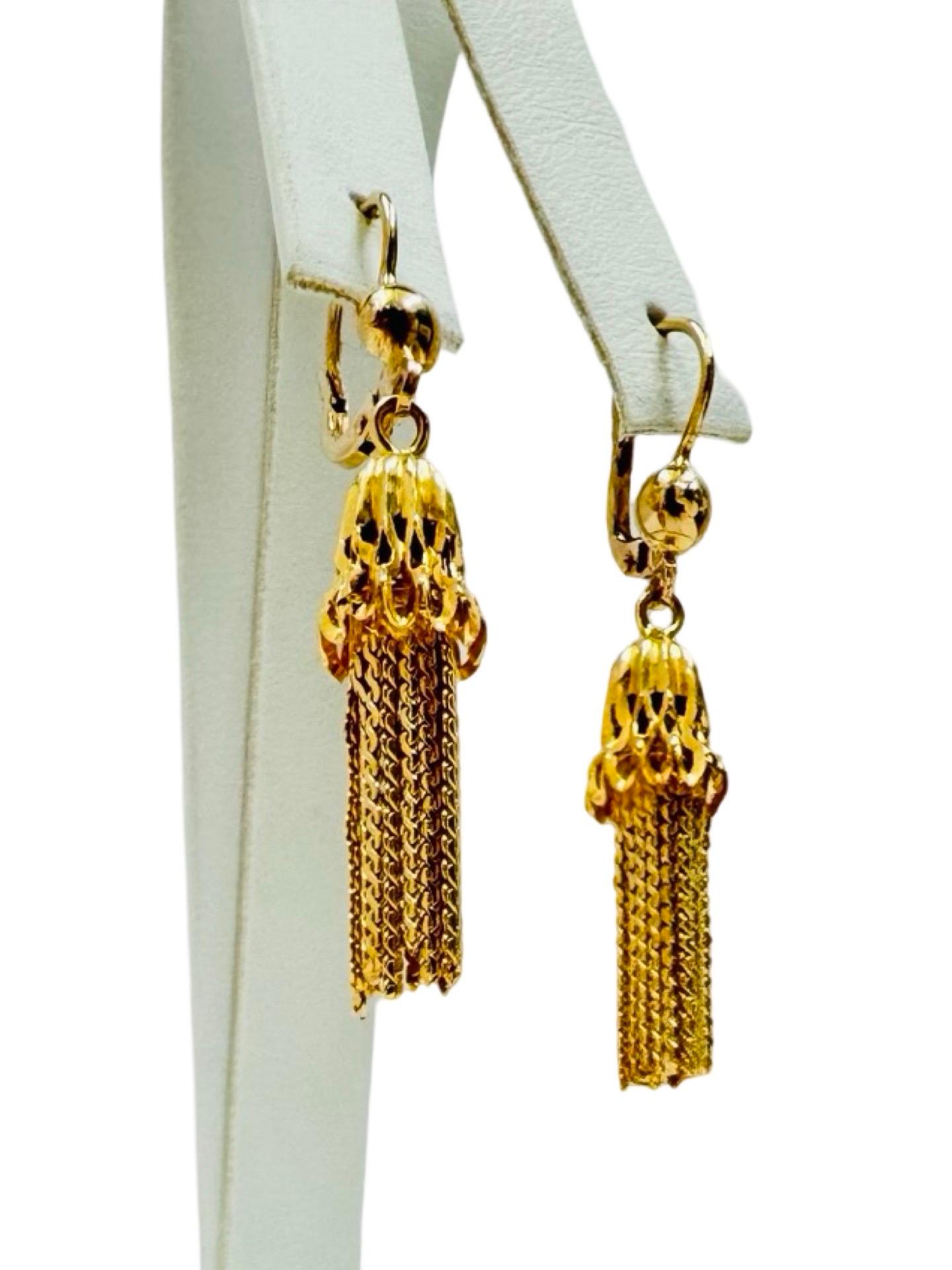 These elegant vintage drop earrings are crafted in rich 18 karat yellow gold and showcase a beautifully detailed tassel design. Each earring features an openwork cap from which delicate gold chain fringe flows, creating graceful movement and an