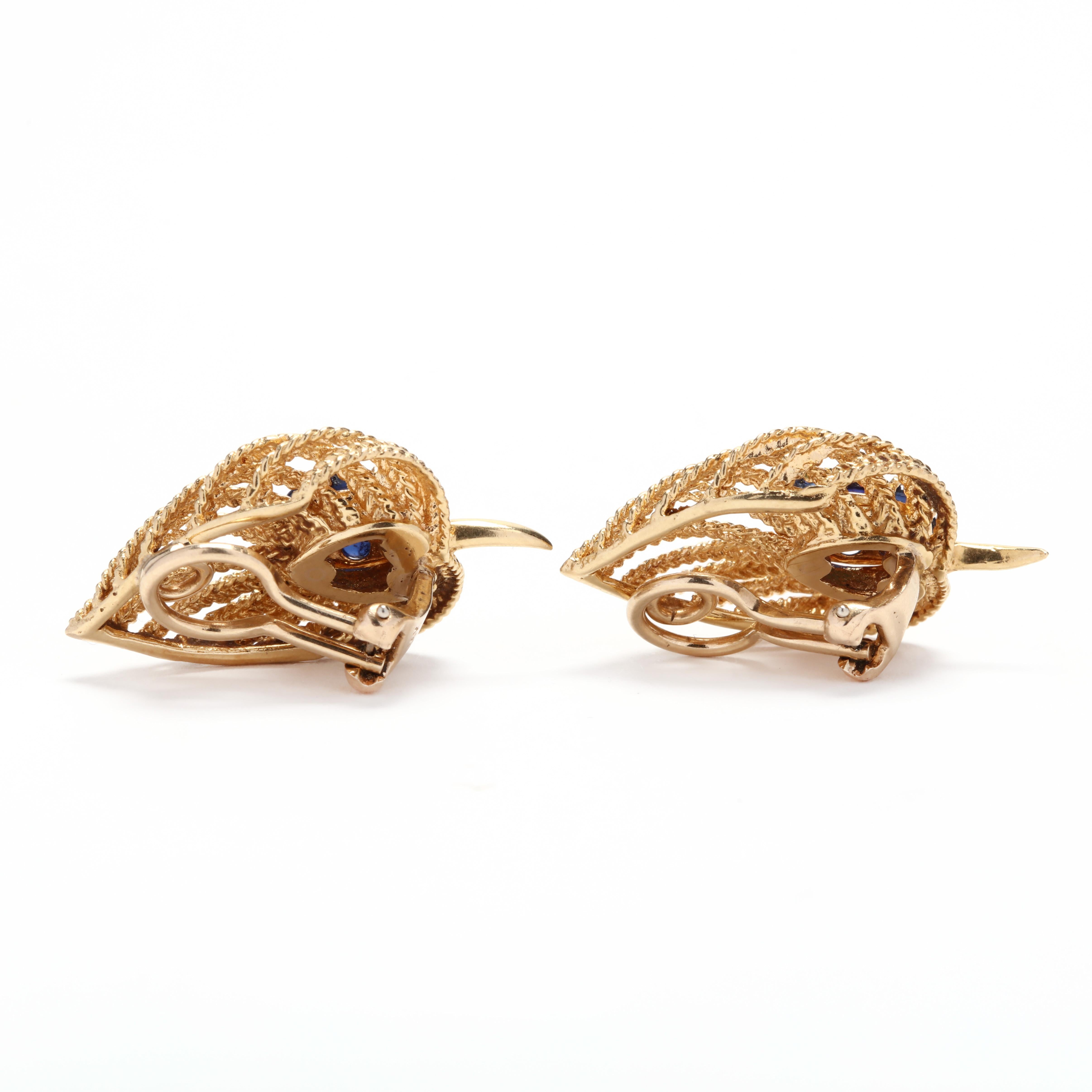 A pair of vintage 18 karat yellow gold, turquoise and sapphire leaf clip on earrings. These earrings feature an open work, braid motif leaf design each with two round, cabochon turquoise stones surrounded by round, cabochon sapphire stones and with