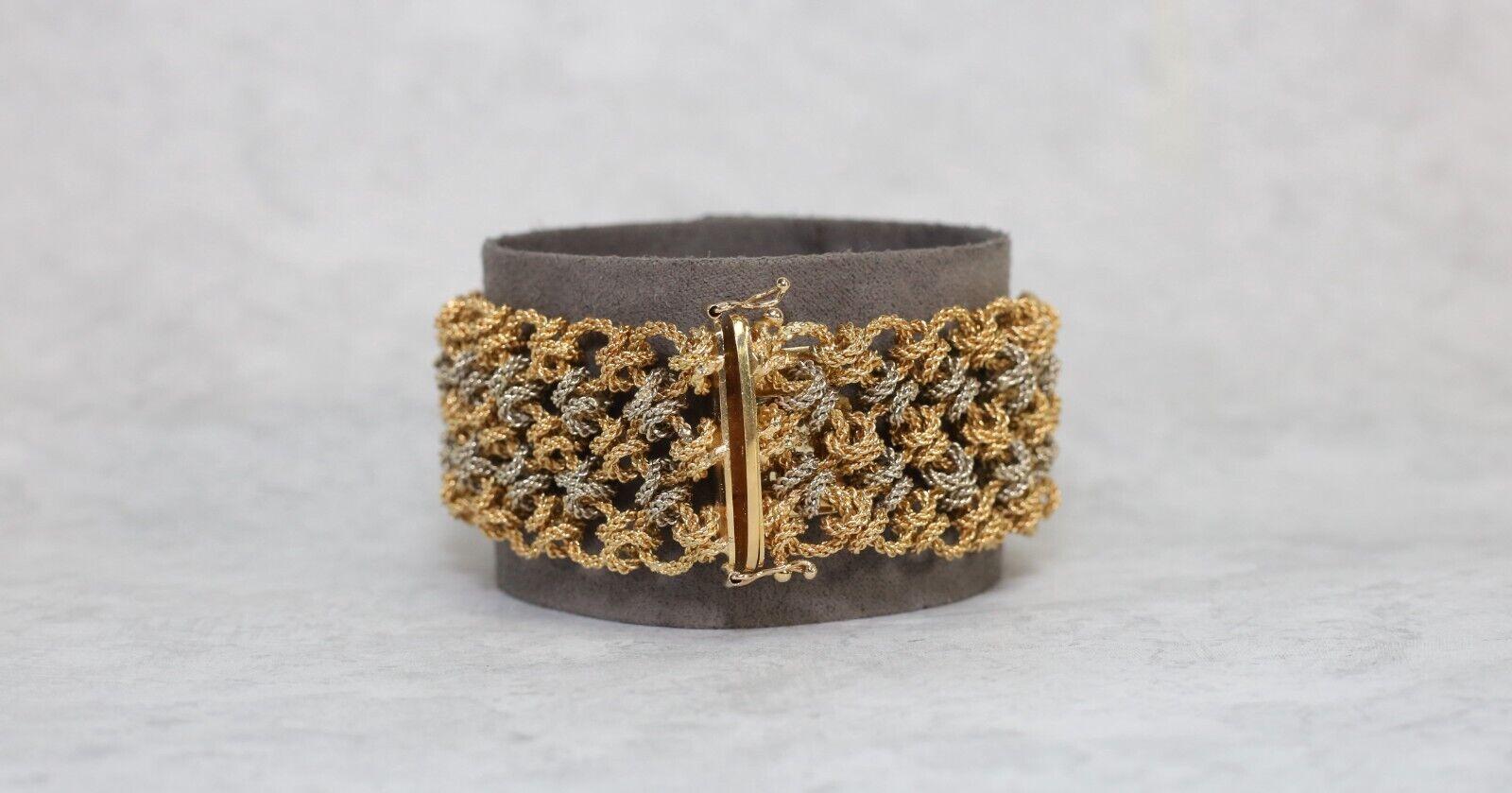 Enhance your wardrobe with this elegant heavy woven vintage bracelet. Hand crafted in a high quality 18k gold, this bracelet showcases an array of textured and highly detailed rings of yellow and white gold. The bracelet consists of three rows with