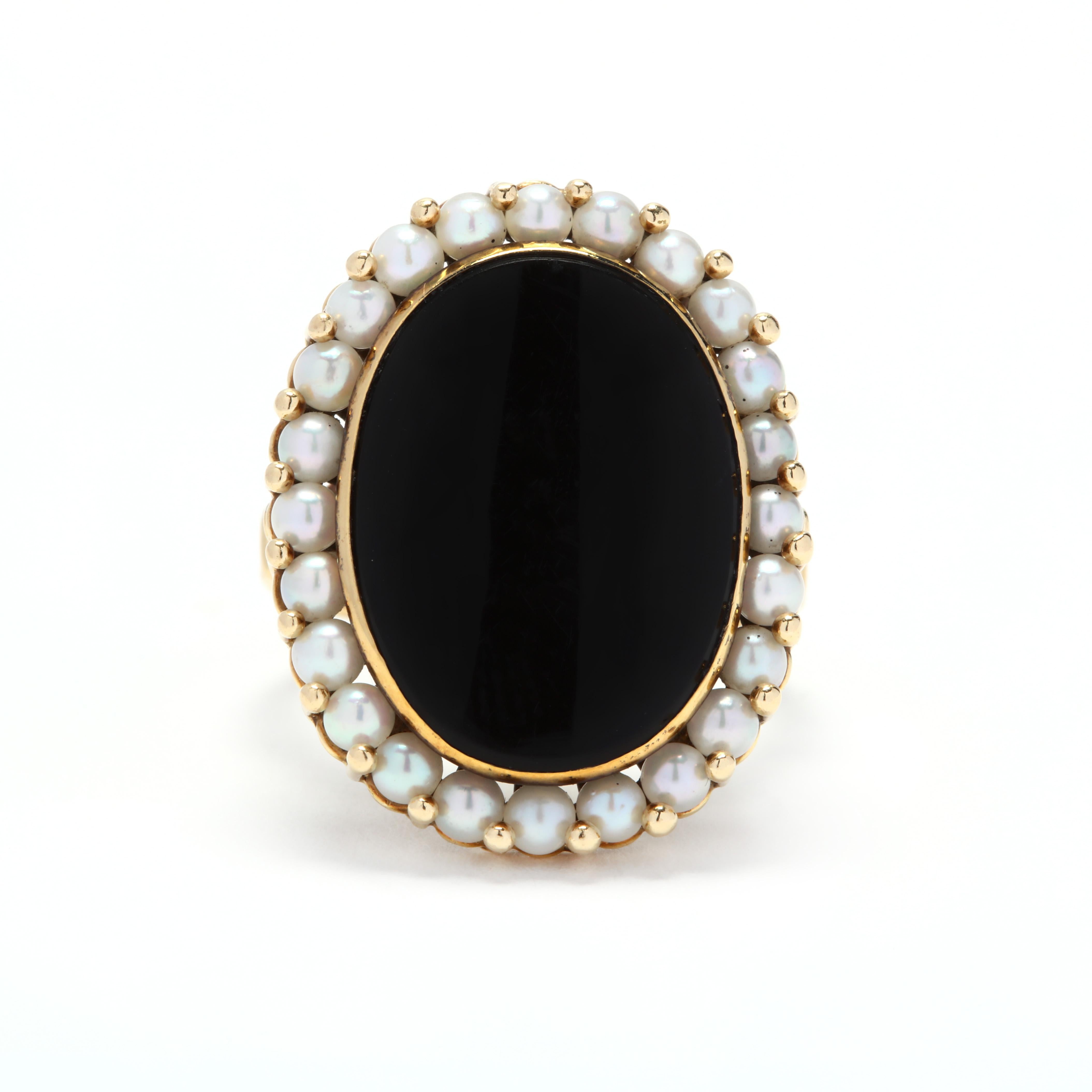 A vintage 18 karat yellow gold, black onyx and pearl ring. This ring features a bezel set oval, flat cut black onyx center stone surrounded by a halo of pearls.

Stones:
- black onyx, 1 stone
- oval flat cut
- 20 x 15 mm

- pearls, 24 stones
-