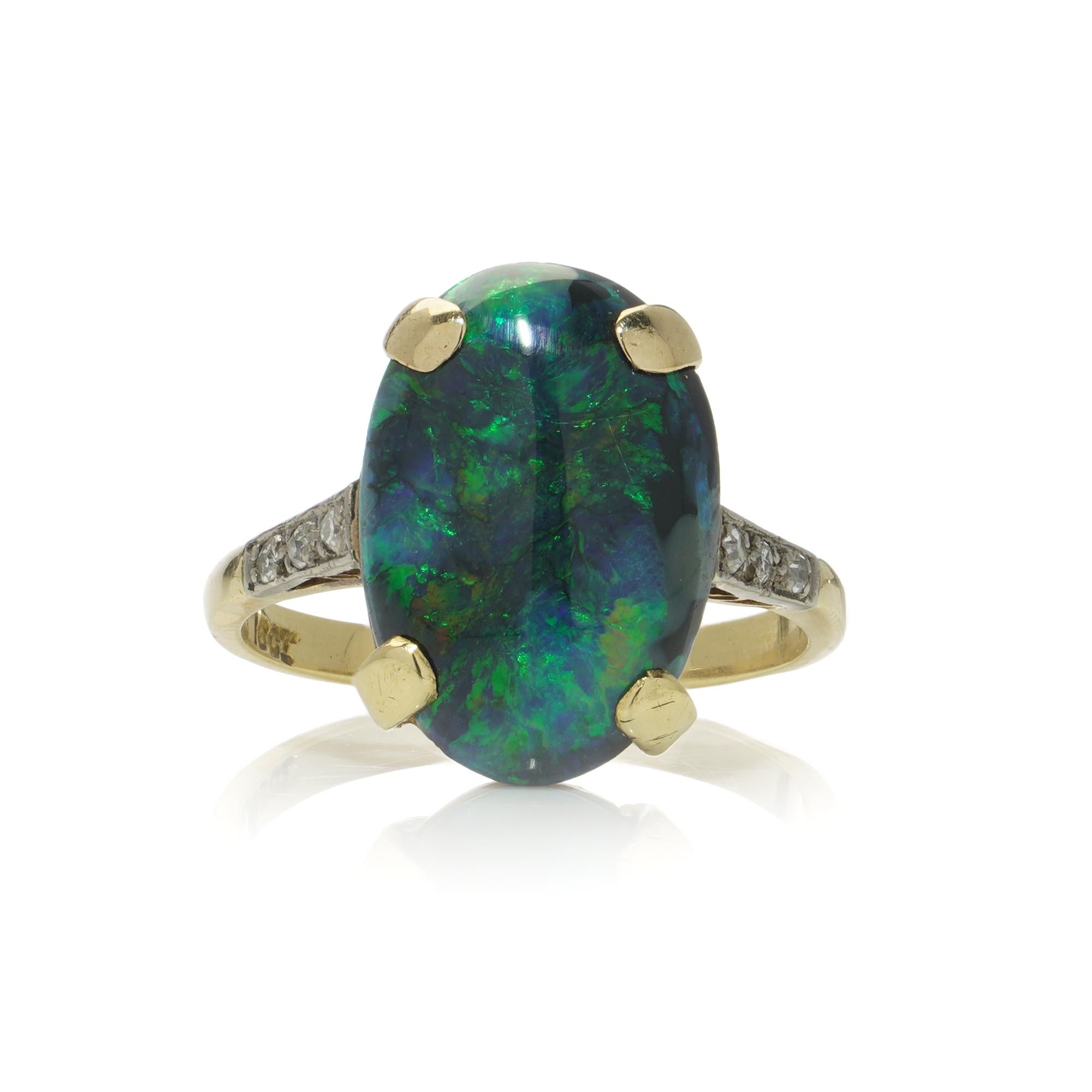 Vintage 18kt gold black opal and diamond ring.

Made in Circa 1960 - 1970s.
Hallmarked with 18kt gold mark.

The ring features a cabochon-cut black opal.
The opal is securely set in a four-claw setting.
The shoulders are adorned with round brilliant