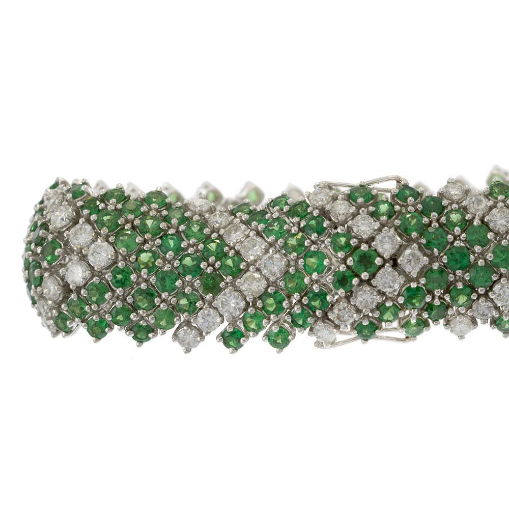 This extraordinary vintage bracelet is a masterpiece of design and craftsmanship, featuring a wide mesh of round-cut green tsavorites arranged in an intricate chevron pattern, accented by sparkling white diamonds. Crafted in solid 18KT white gold,
