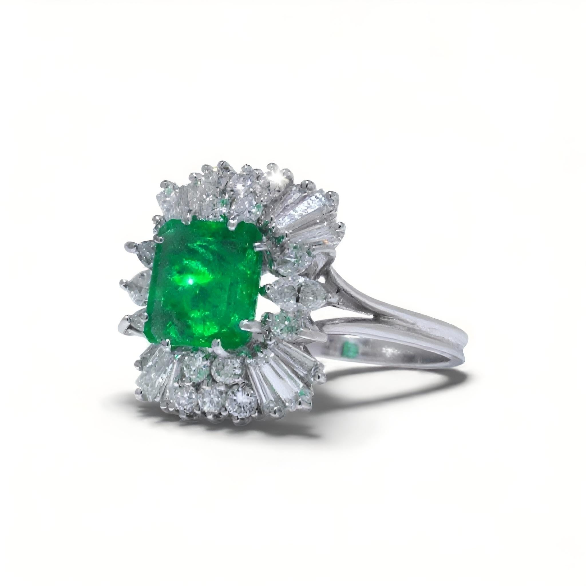 A vintage 18KT white gold Colombian emerald and diamond cluster ring from the 1970s, featuring a vivid natural emerald framed by a striking multi-cut diamond surround. This handcrafted piece showcases a high-saturation Colombian emerald, a gemstone