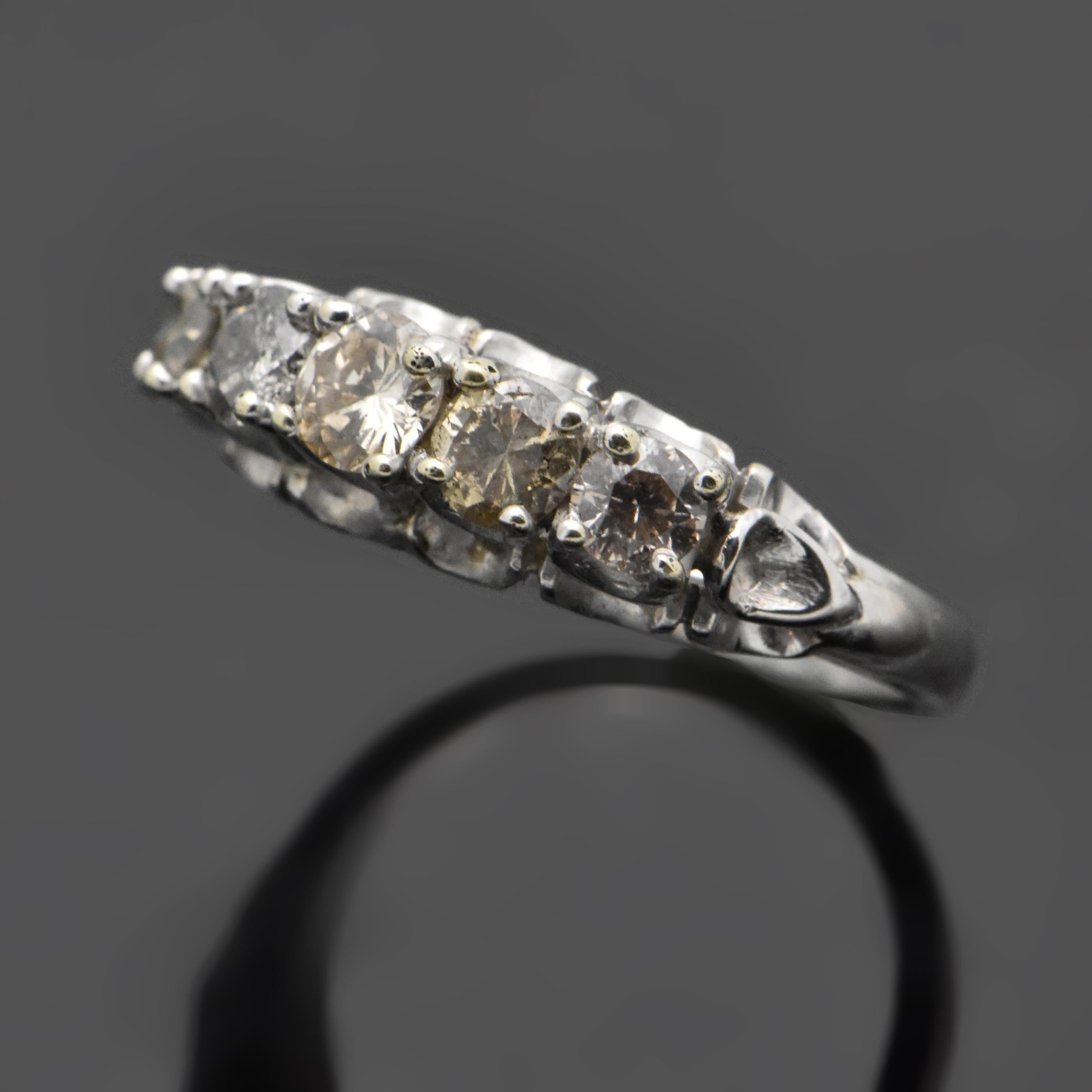 This ring is a vintage 18kt white gold ring featuring five brilliant-cut diamonds with an estimated 0.83 cttw. Estimated weight of gold is 2.5 gr. 
We will size it for you.

