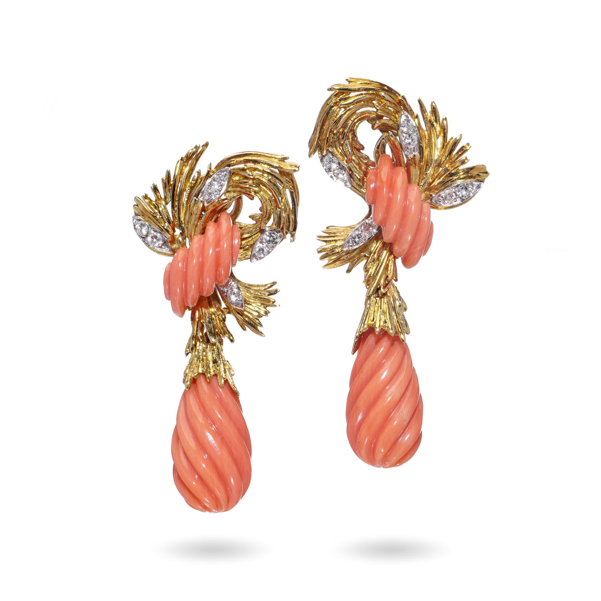 Un audace e scultoreo paio di orecchini vintage degli anni '70, realizzati in ricco oro giallo 18kt. Ogni orecchino presenta due elementi in corallo naturale splendidamente intagliati: una goccia scanalata e un motivo a voluta. Il corallo presenta