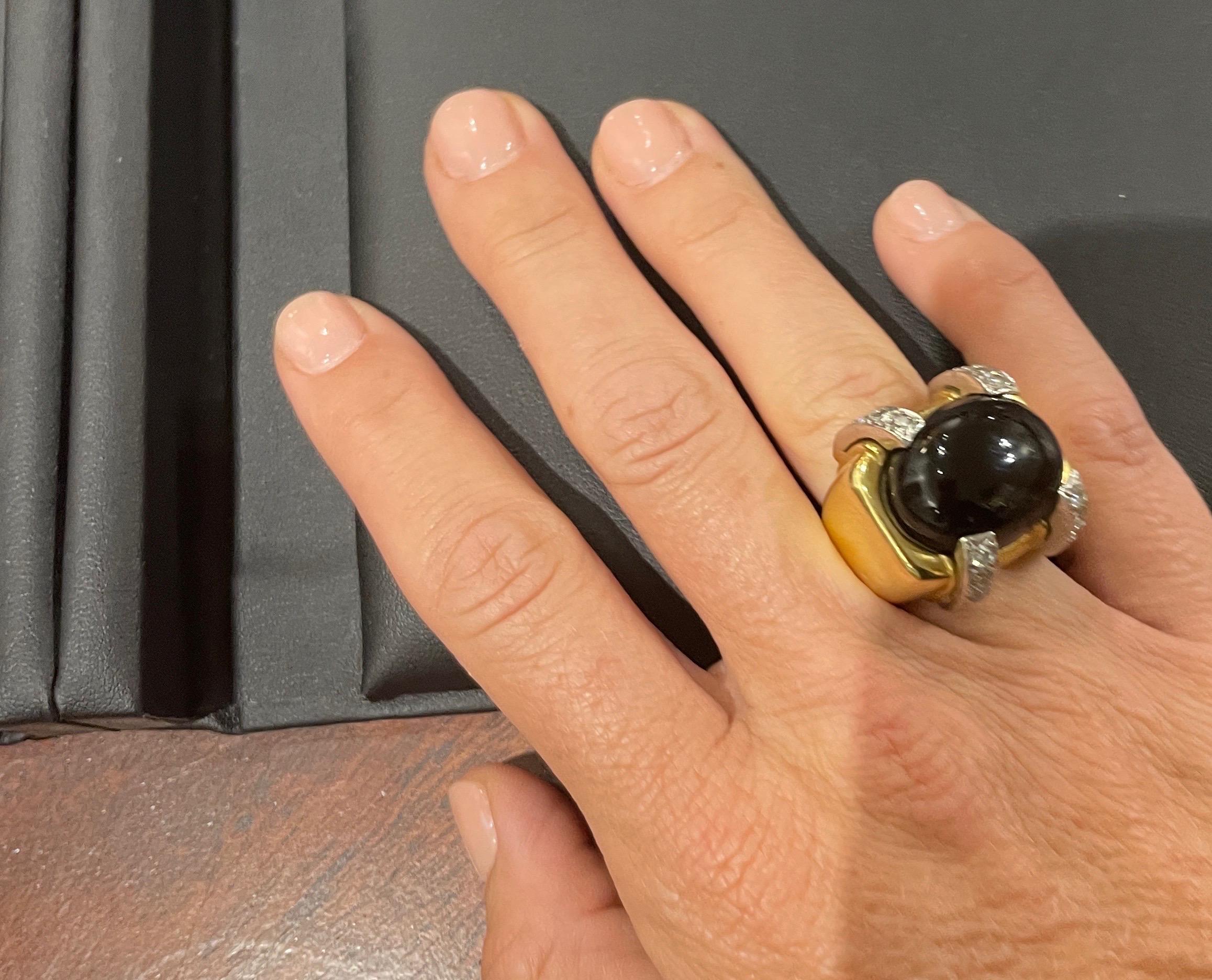 In David Webb style,  this gorgeous 18k yellow gold ring features a beautiful oval cabochon-cut black onyx accented by round brilliant-cut diamonds weighing approximately 0.48 carats in total. The ring does have a flexible guard band on the inside