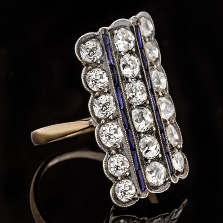stunning antique ring with old cut diamonds and rare French cut sapphires! The ring is set with 18 sparkling old mine cut diamonds arranged in 3 columns, weighing approximately 2 carats combined. 

The weight is approximate as it was determined by