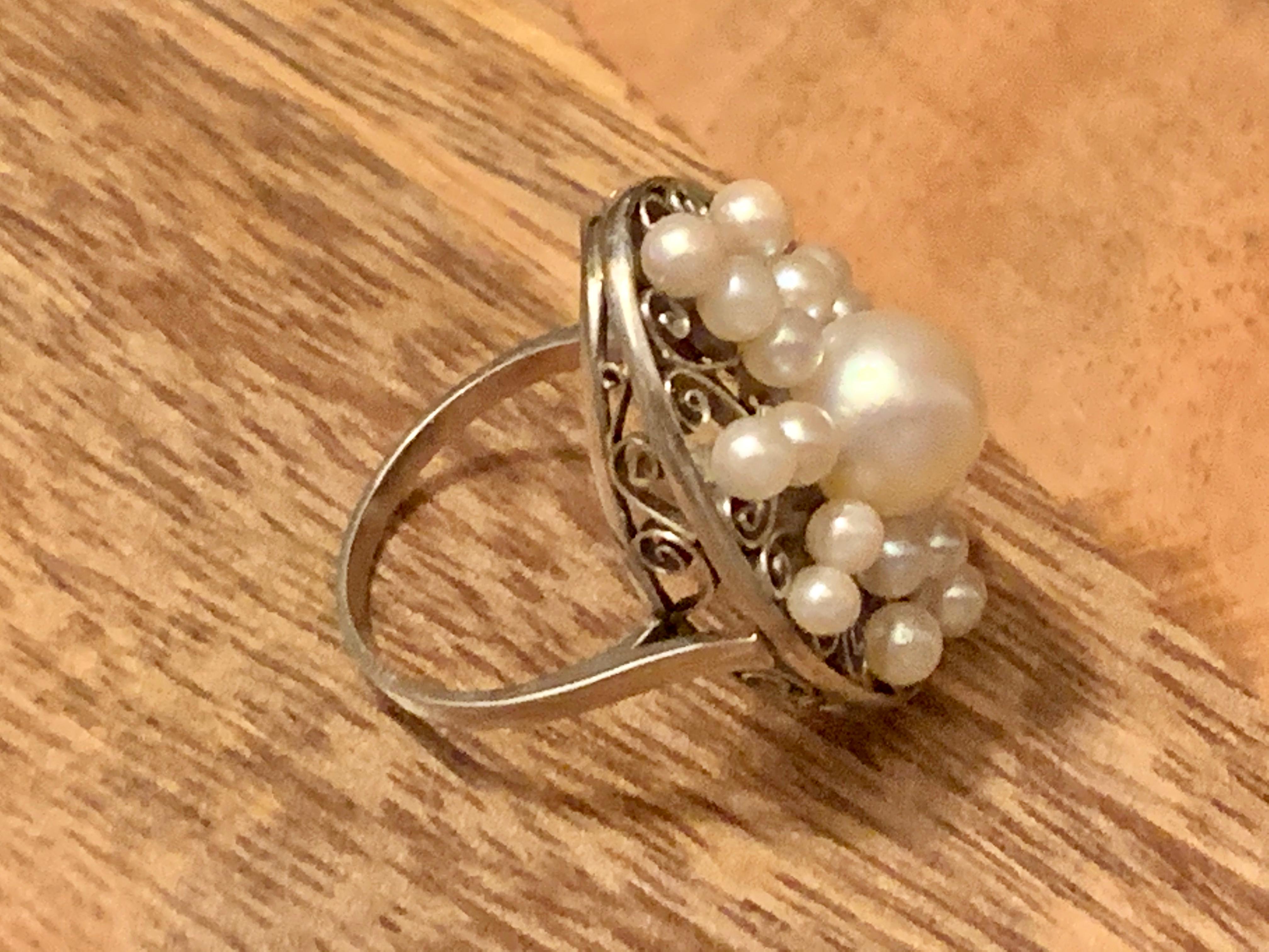 This lovely 1910-1930's vintage ring reminds me of a winter snowflake, or a summer flower.  It features 19 cultured Pearls.  There is one large Pearl in the center, with the remaining radiating out from the center Pearl, almost like rays of