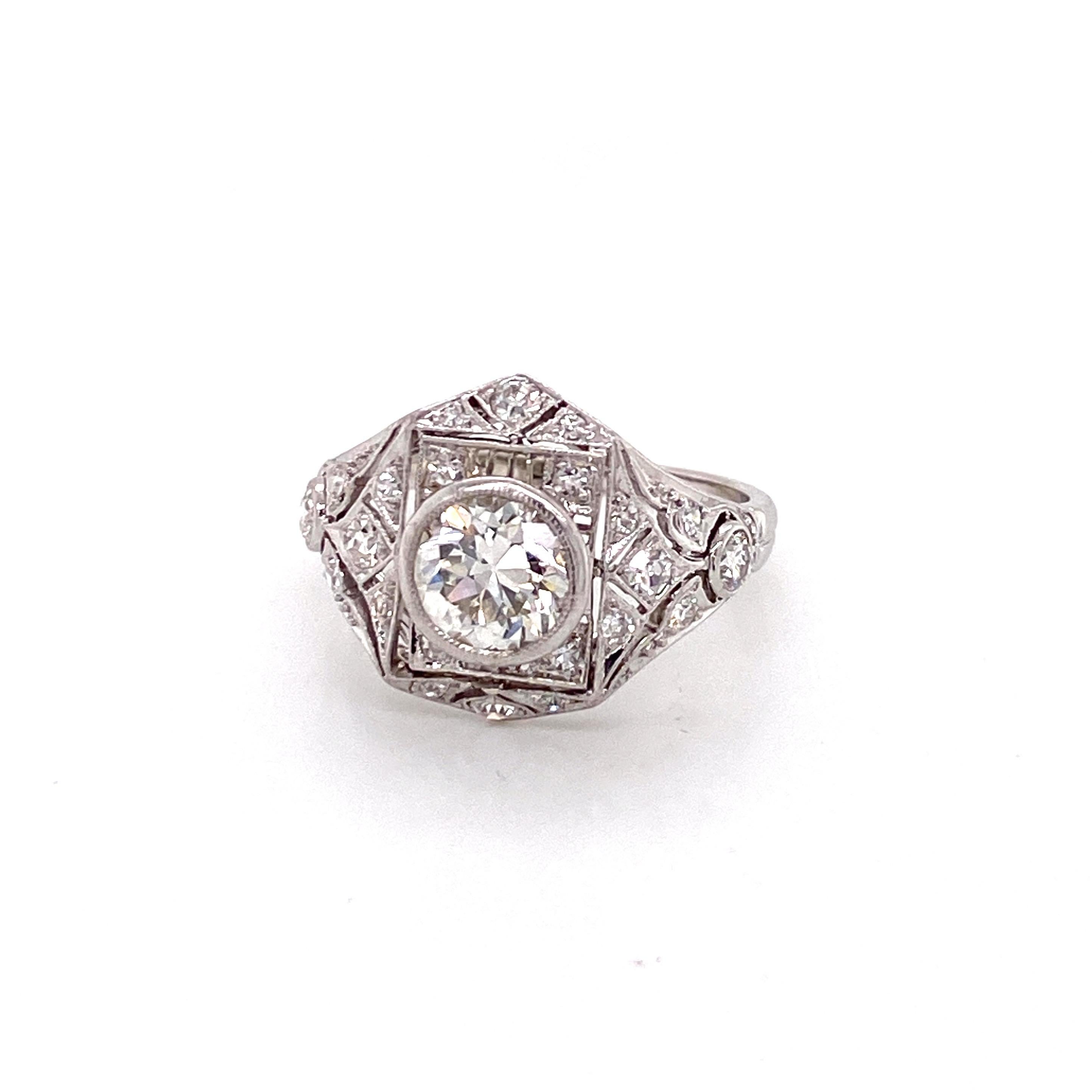 A magnificent representation of the artistry and opulence of the Jazz Age, this exquisite vintage ring dates back to the iconic 1920s. The showstopping centerpiece is a breathtaking European cut diamond weighing approximately 1.25 carats. With its