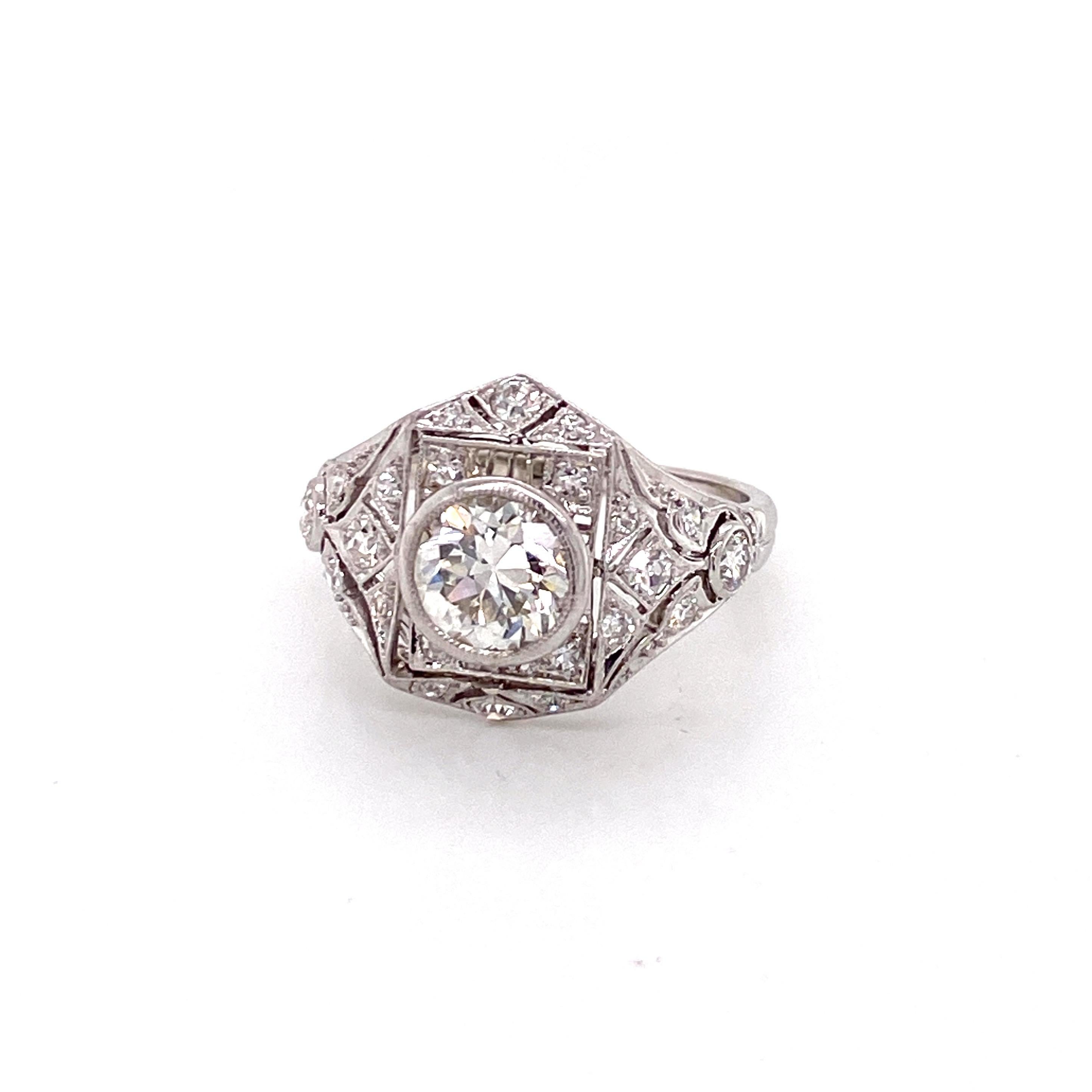 Una magnifica rappresentazione della maestria e dell'opulenza dell'Età del Jazz, questo squisito anello d'epoca risale agli iconici anni '20. Il pezzo forte è un diamante mozzafiato a taglio europeo del peso di circa 1,25 carati. Con il suo caldo