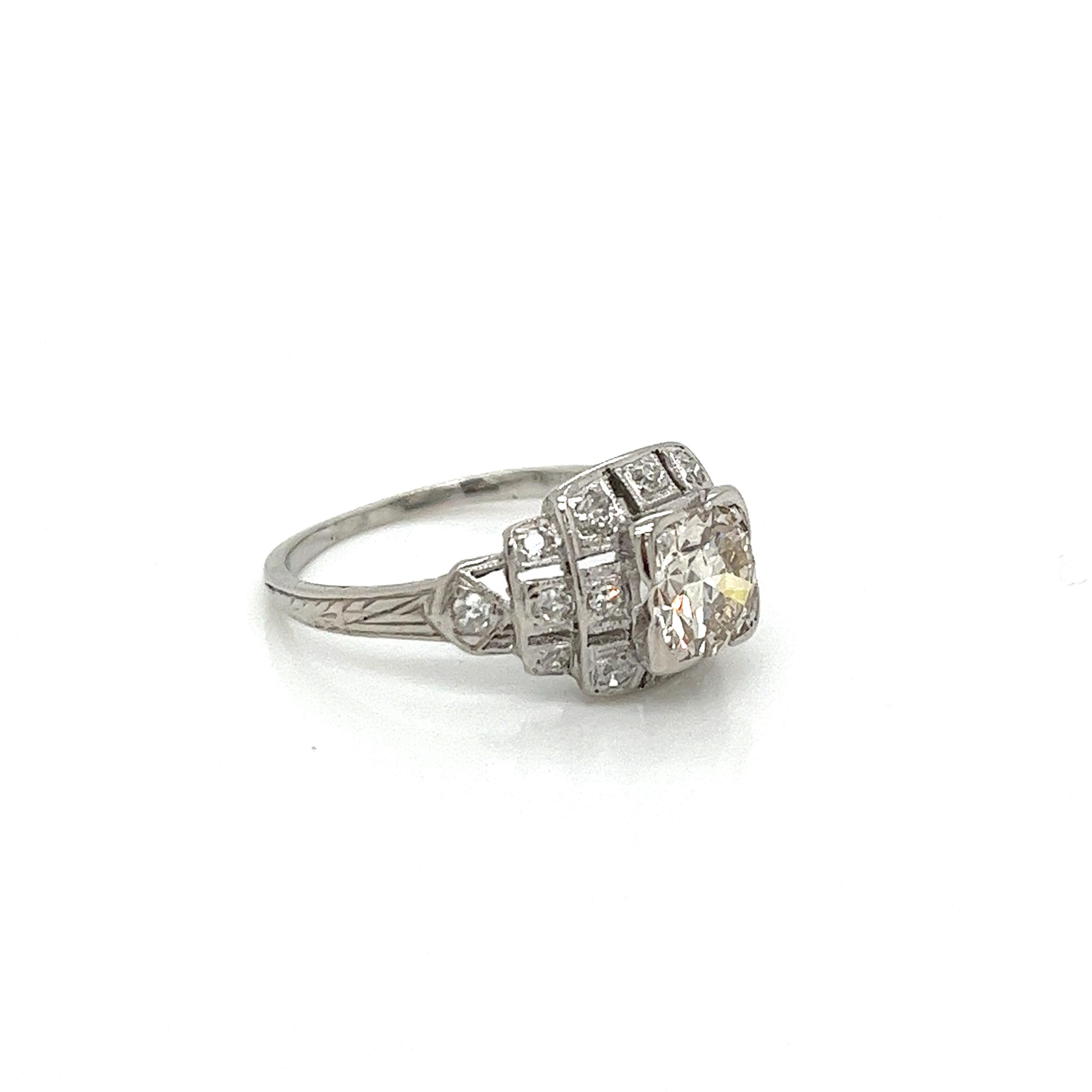 This exquisite platinum ring is a stunning example of Art Deco elegance. The centerpiece is a sparkling old European cut diamond weighing approximately 0.82 carats. Its warm K color is complemented by its SI1 clarity, allowing the diamond to truly