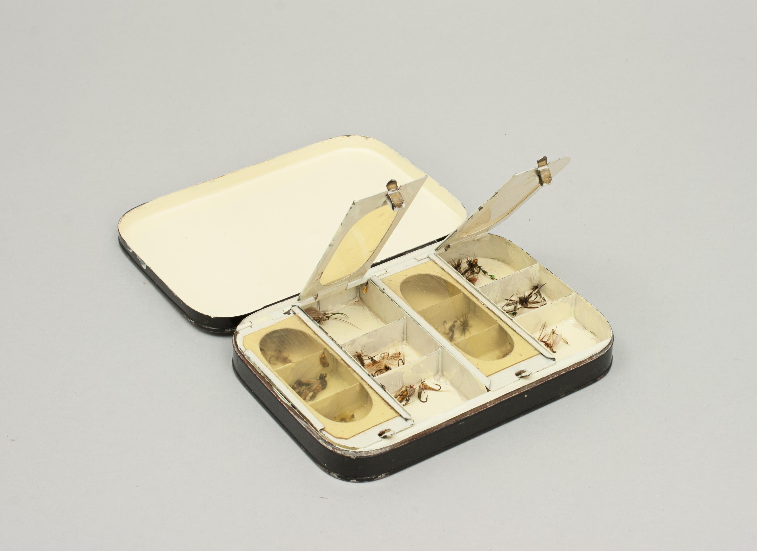 Vintage black Japanned dry fly fishing box.
A black japanned tin fly box with cream interior and four compartments with transparent celluloid lids so that the flies inside may be seen. The lids with clasps to keep the windows closed, some of the