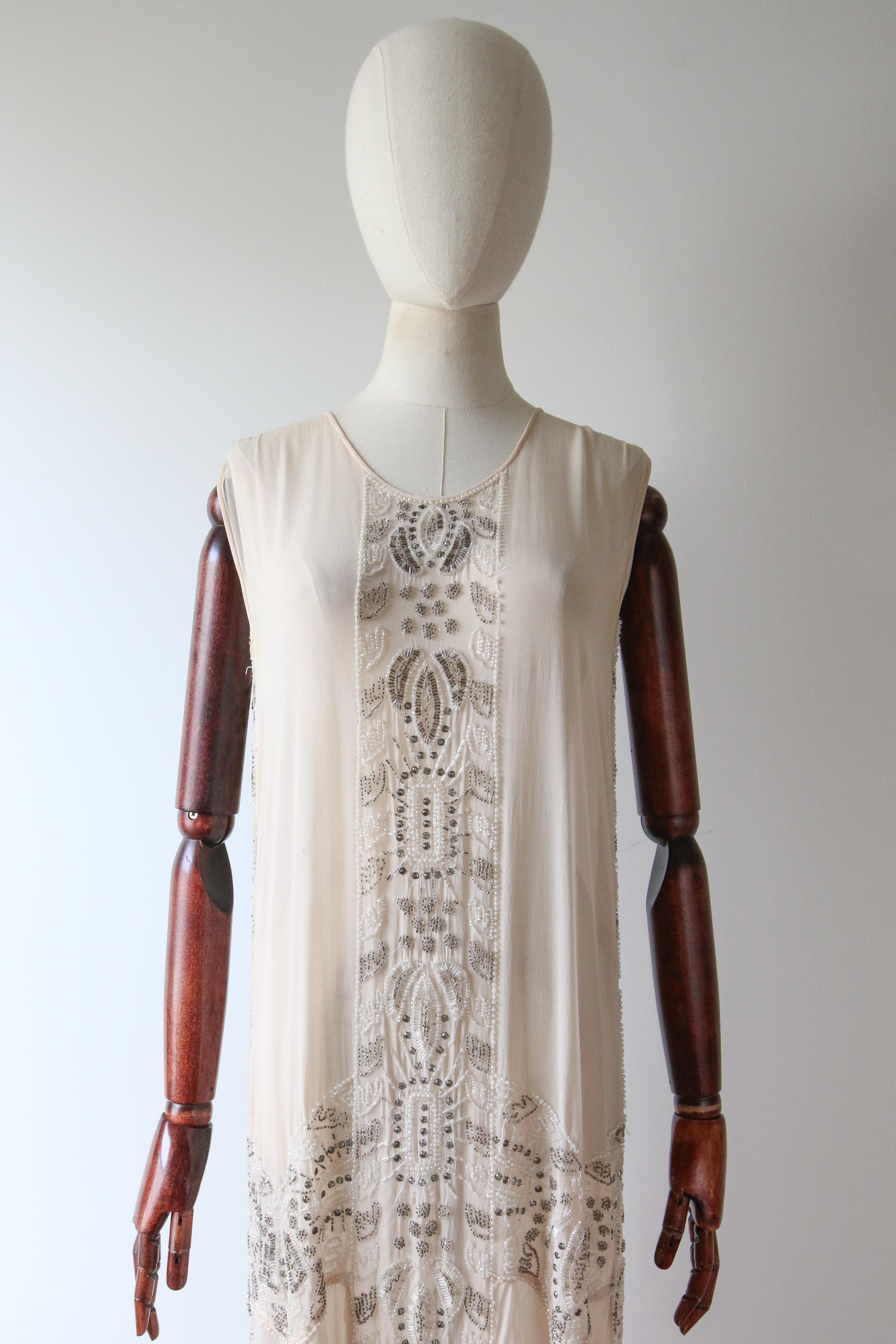 Full of opulent original details, rendered in the most luxurious fashion, this rare 1920's piece is a beauty to behold .

The rounded neckline is framed by wide shoulder straps and a sleeveless cut. The simple straight-line bodice is accented by a