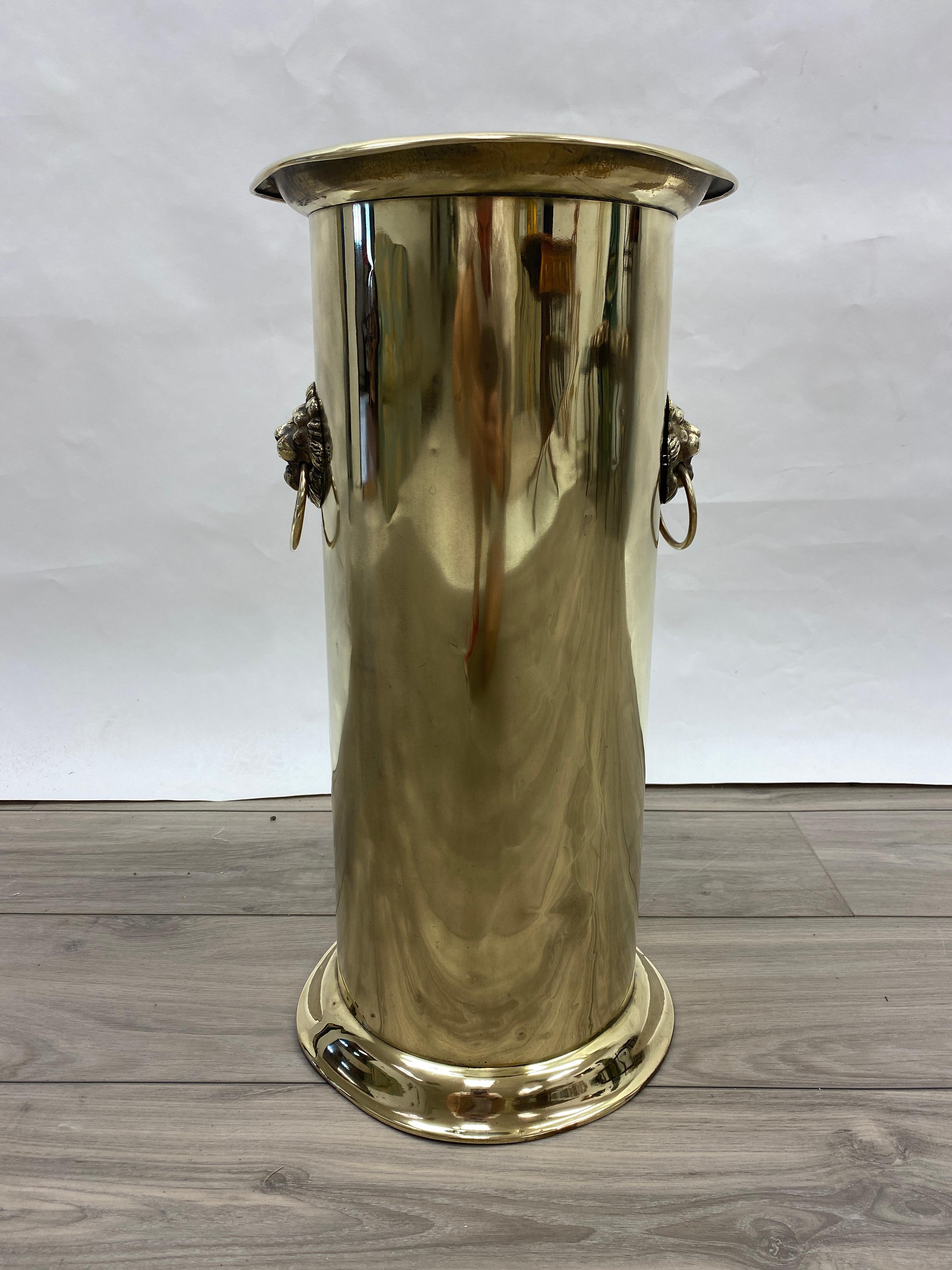A handsome vintage solid brass umbrella stand adorned with lions head ring pulls on both sides. This one is well used with dents and wear from 100 years of umbrella use.